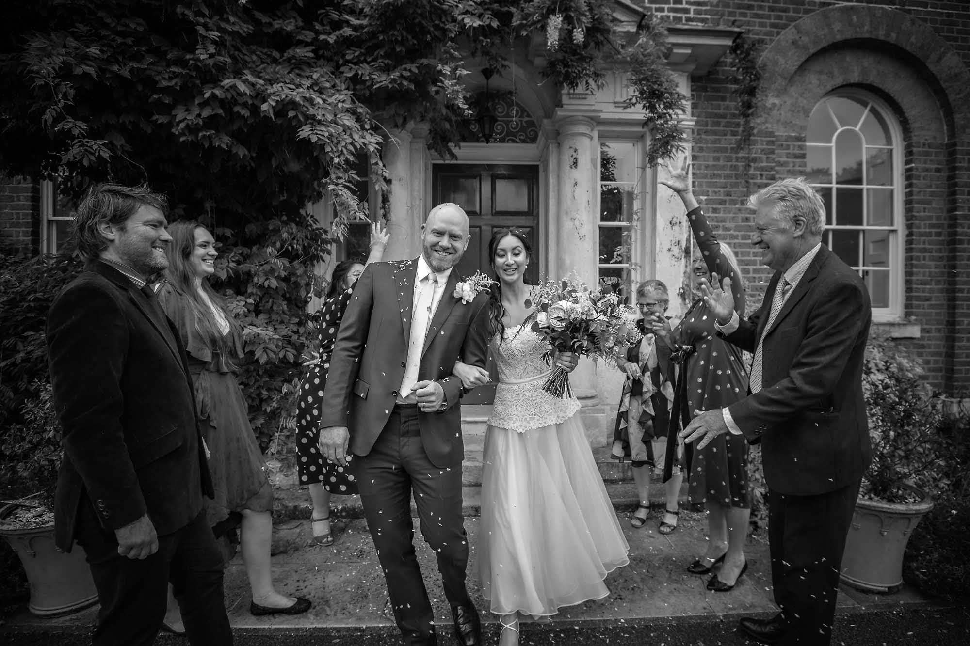 Wedding couple having their confetti thrown whilst leaving Morden Park House in South London