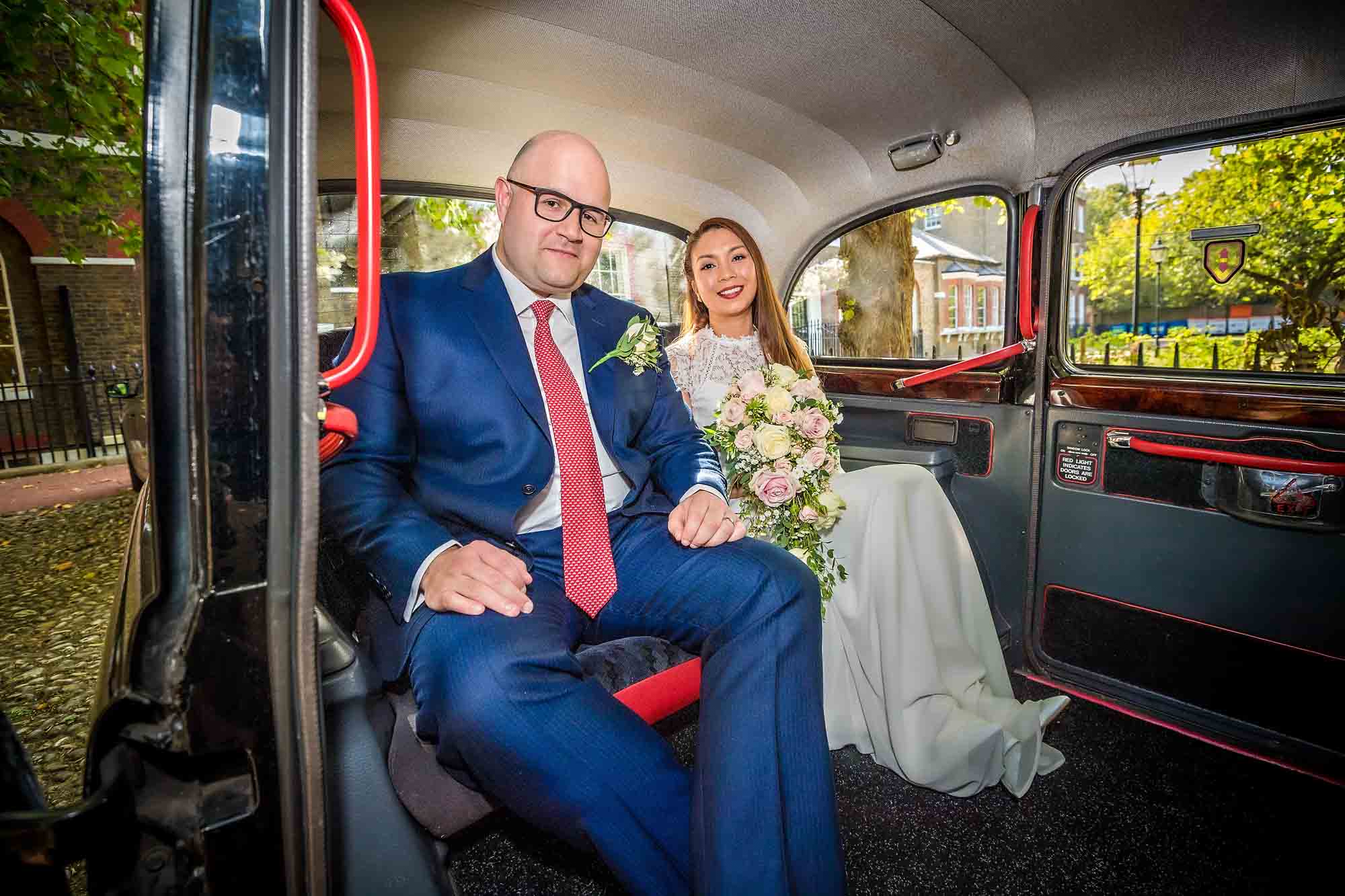 Portrait of wedding couple taken inside black taxi cab outside Southwark Register Office