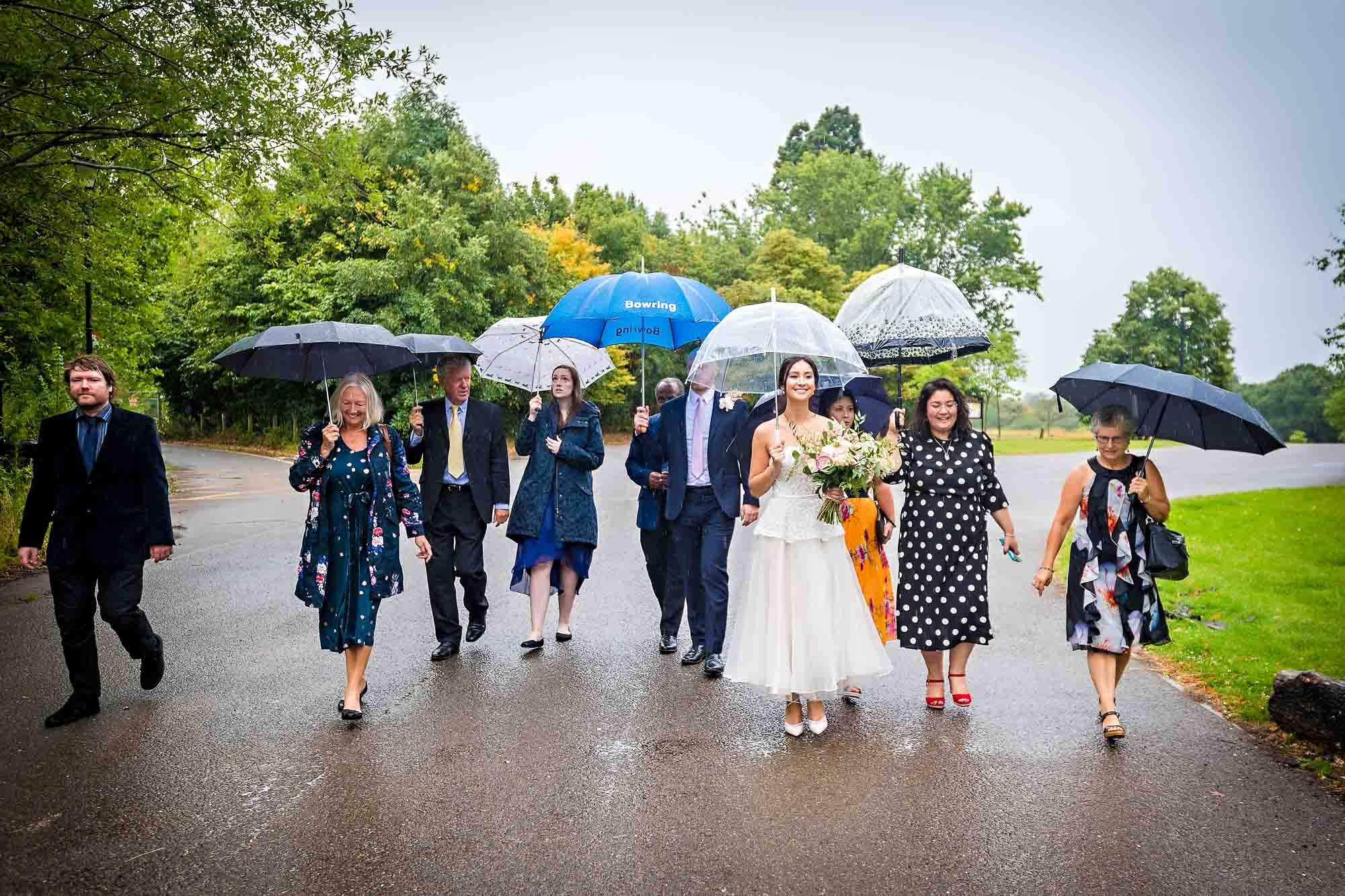 The bridal party leave Merton Register Office in the rain with their umbrellas