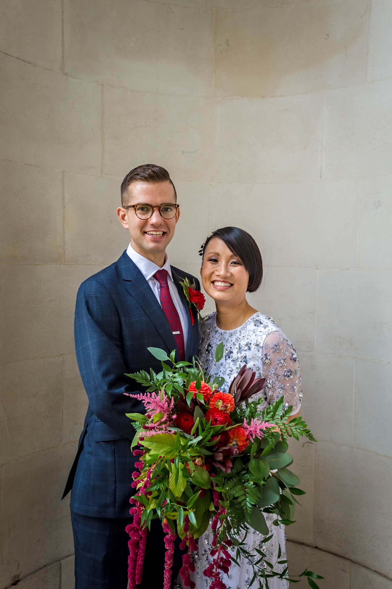 Smiling newly-weds posing with large bouquet outside Old Marylebone Town Hall