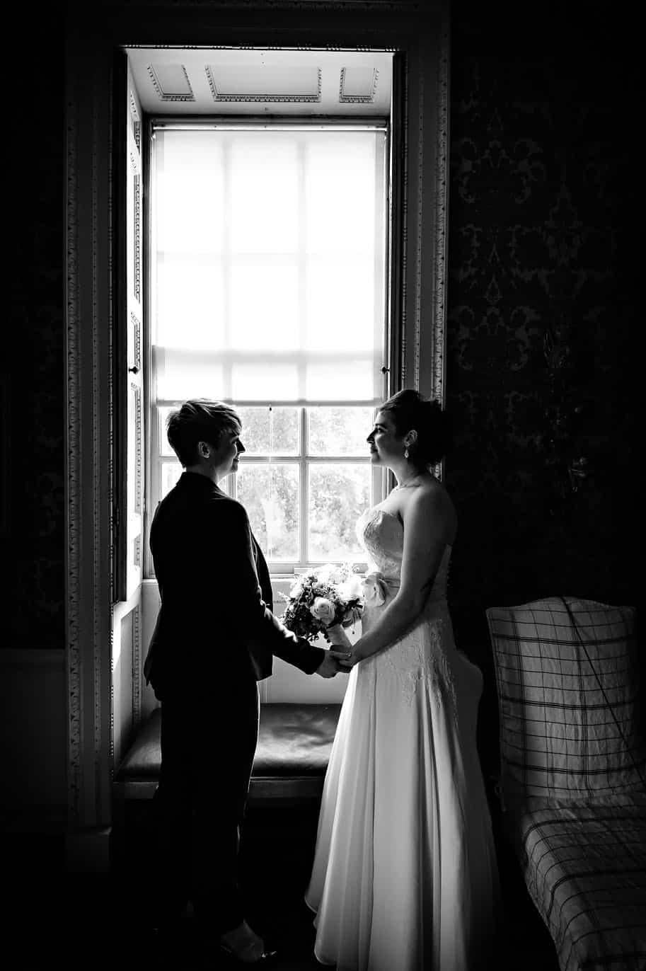 Black and White LGBT/Gay Wedding Photography - Female Couple Holding Hands In Front of Window