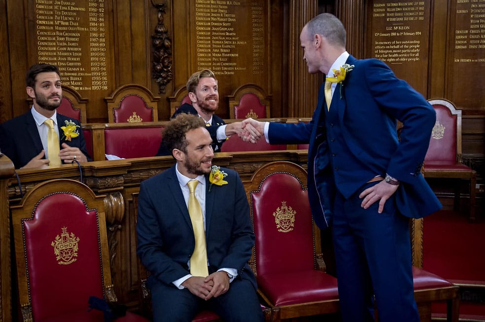 Groom shaking hands with male guest at wedding in Islington Town Hall