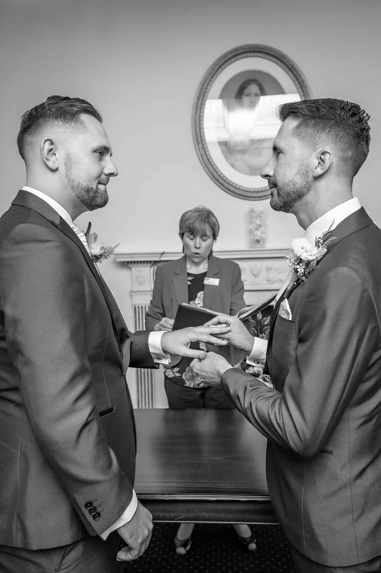 LGBT wedding with groom placing ring on his partner's finger maintaining good eye contact