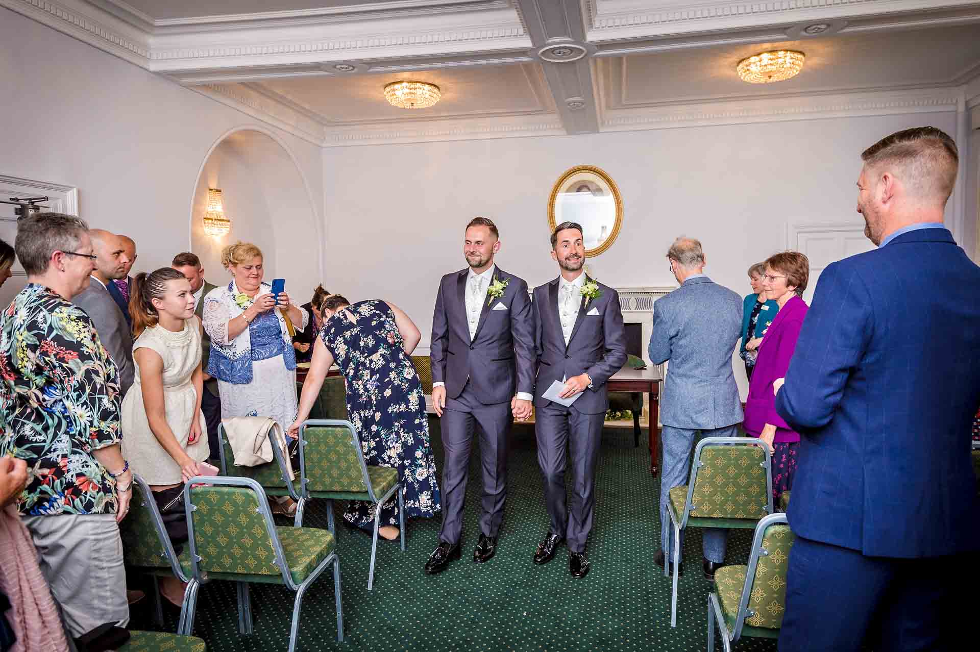 Grooms walking down aisle at register office same-sex wedding