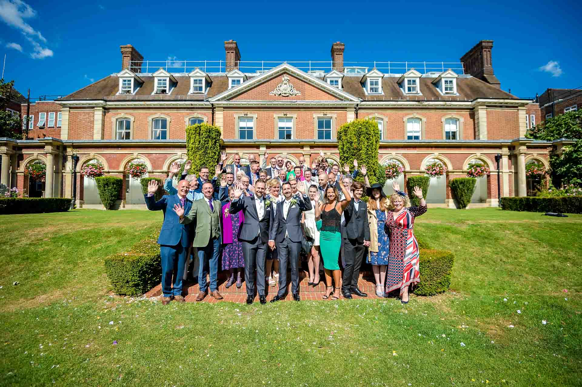 Whole wedding party waving on steps outside the Old Palace at Bromley Civic Centre