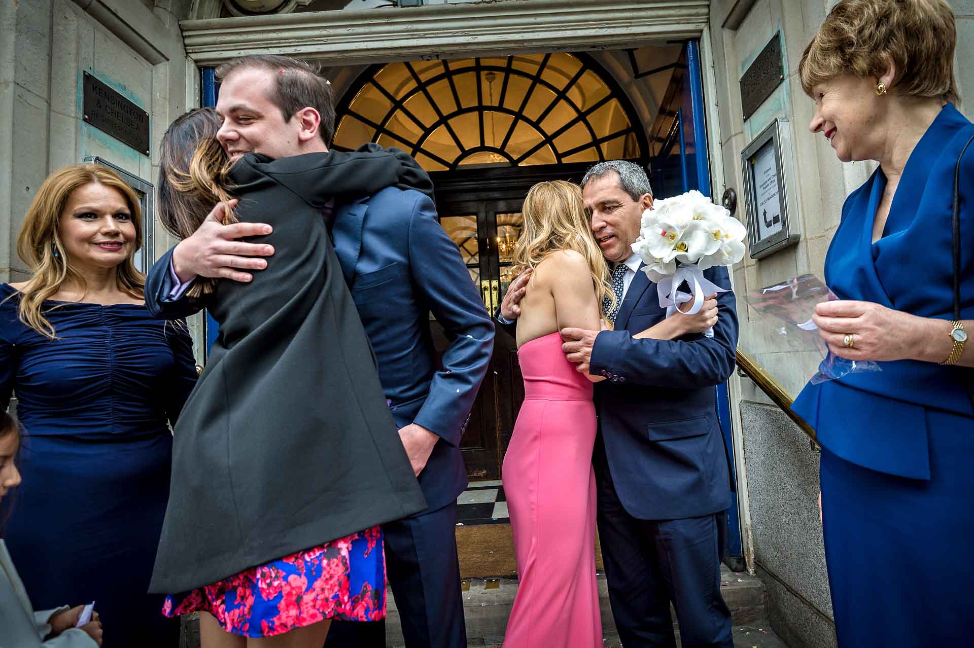 Family and friends hugging couple outside town hall in London