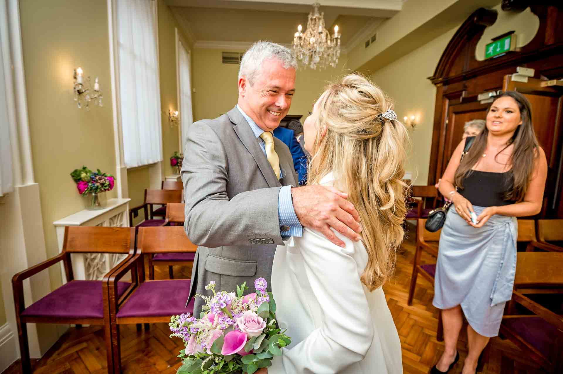 Father holding daughter and giving warm smile at a wedding in the Brydon Room, Chelsea