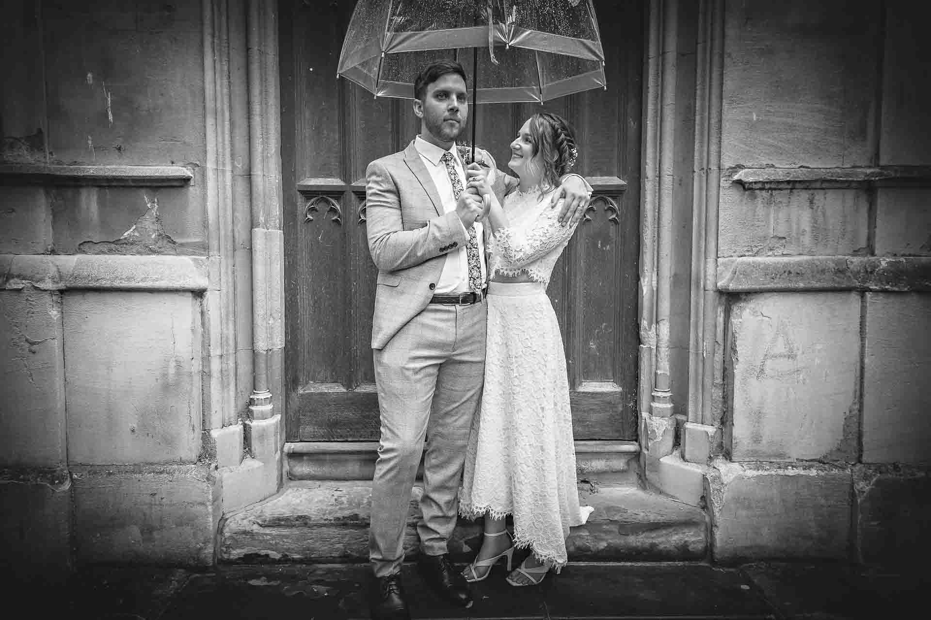 Wedding couple holding umbrella outside St Luke's Church in Chelsea, London