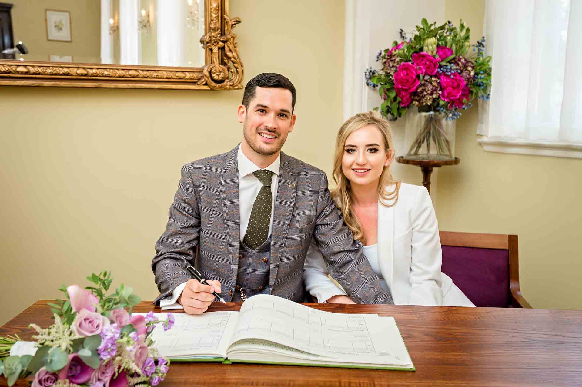 Bride and groom posing with the wedding register at Chelsea Old Town Hall