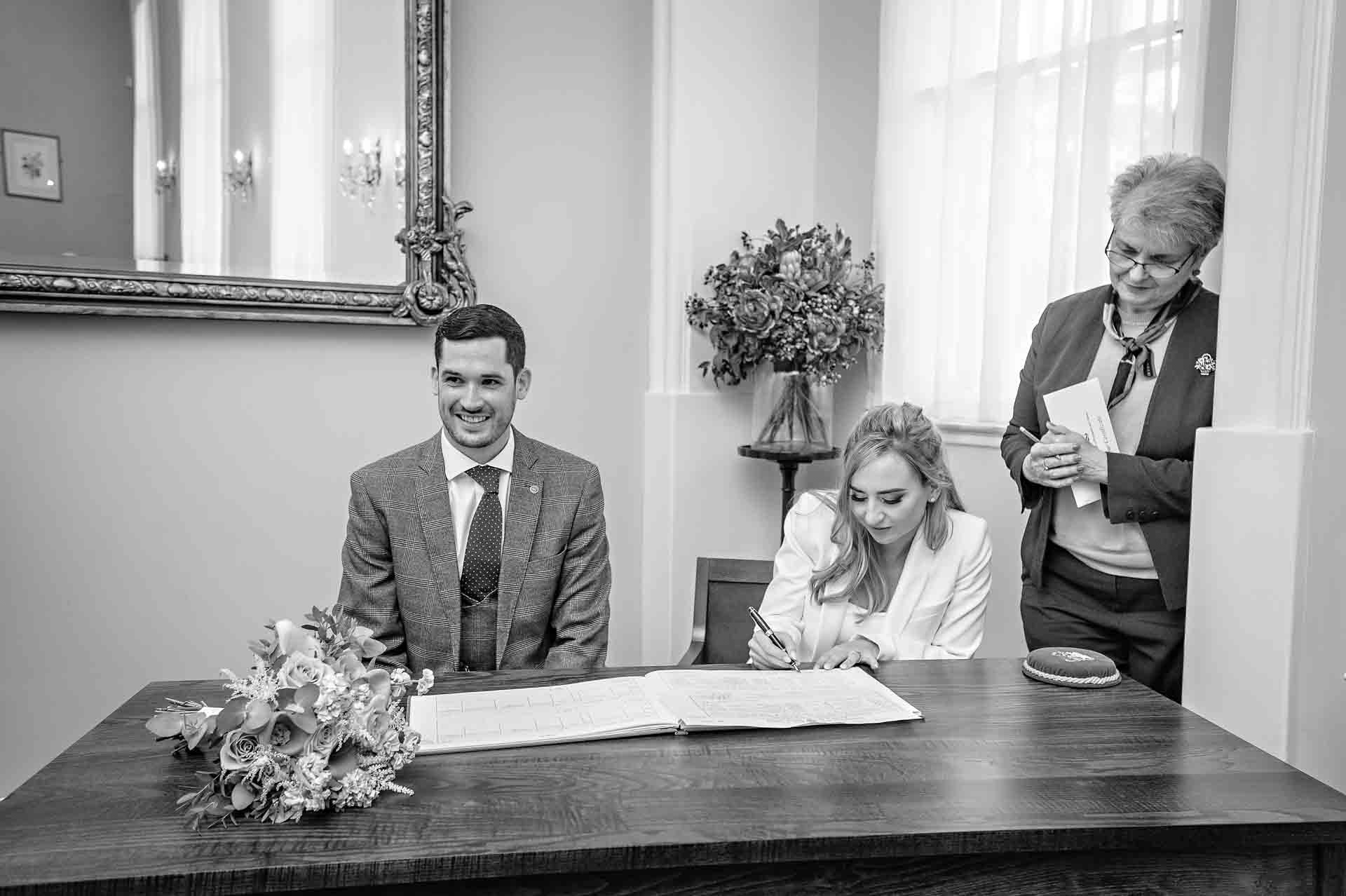 Bride signing the register in Brydon Room, Chelsea Old Town Hall