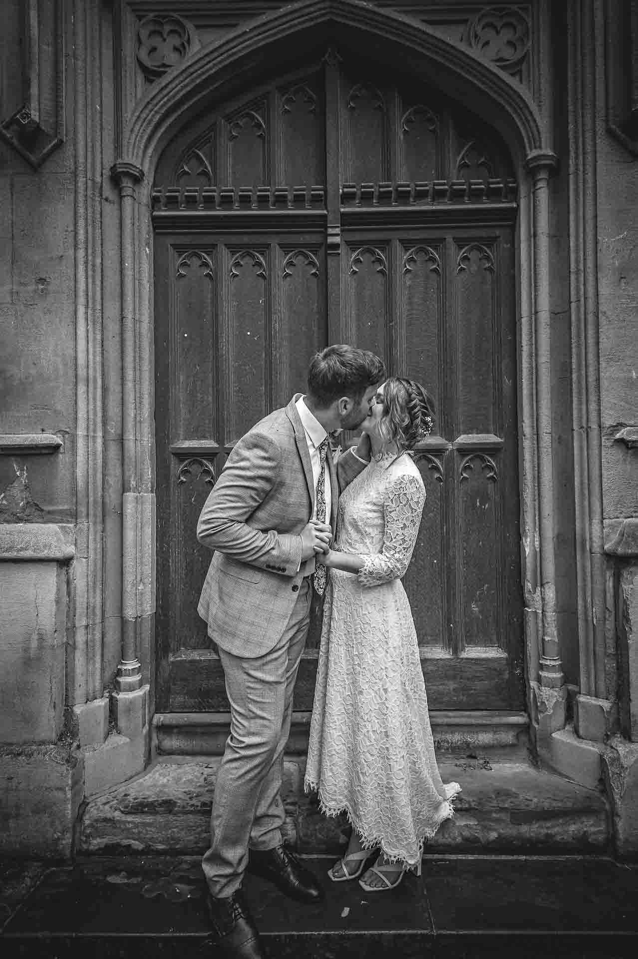 Couple kissing in black and white outside doorway of St Luke's church in Chelsea