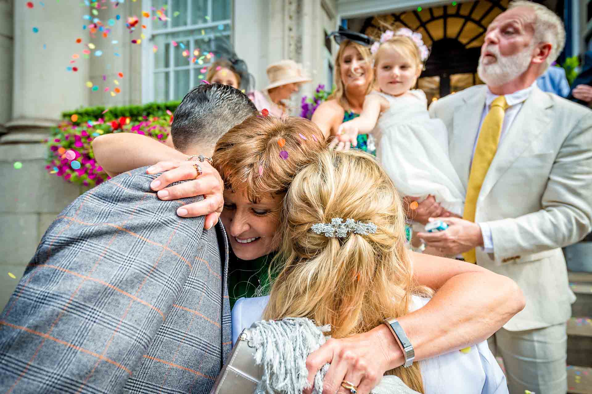 Lady hugging bride and groom outside Kensington and Chelsea Register Office