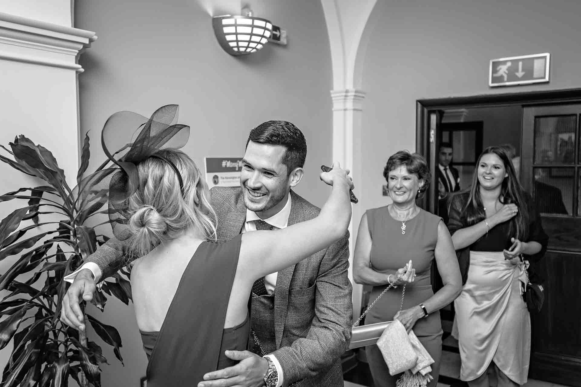 Groom greeting guest with open arms at wedding in London