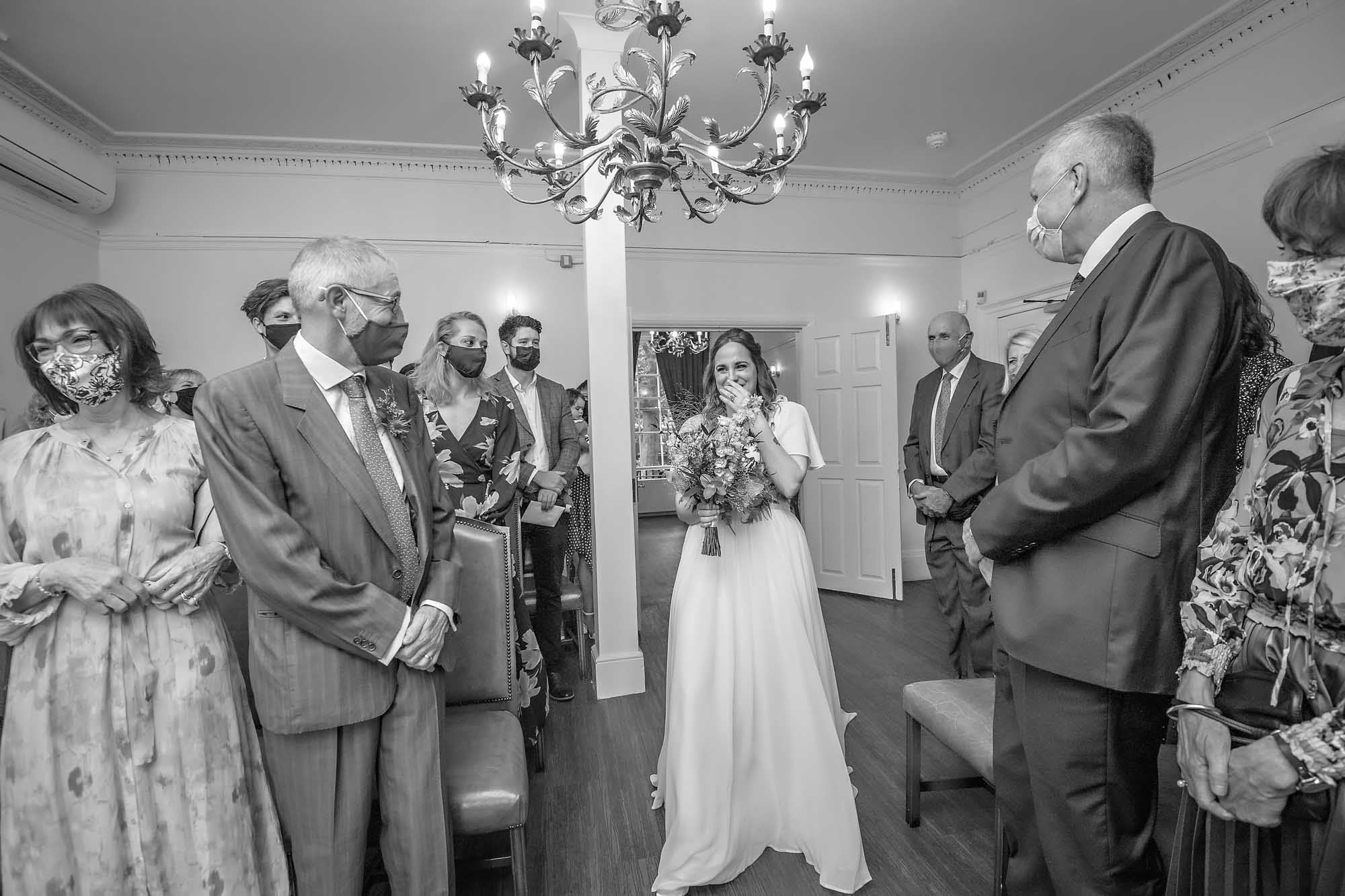 Bride giggling as she walked the aisle whilst guest look on