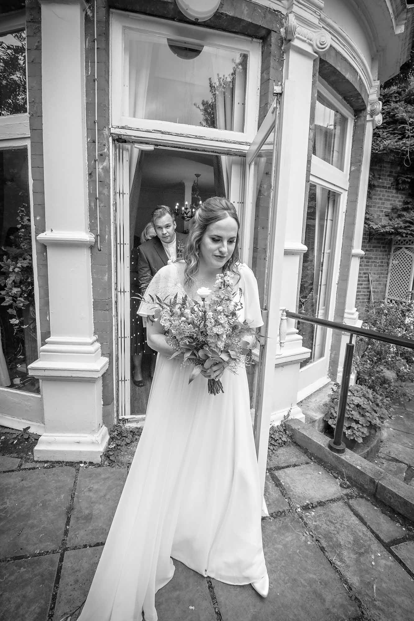 Bride leaving the Garden Room in Southwark as her groom follows behind