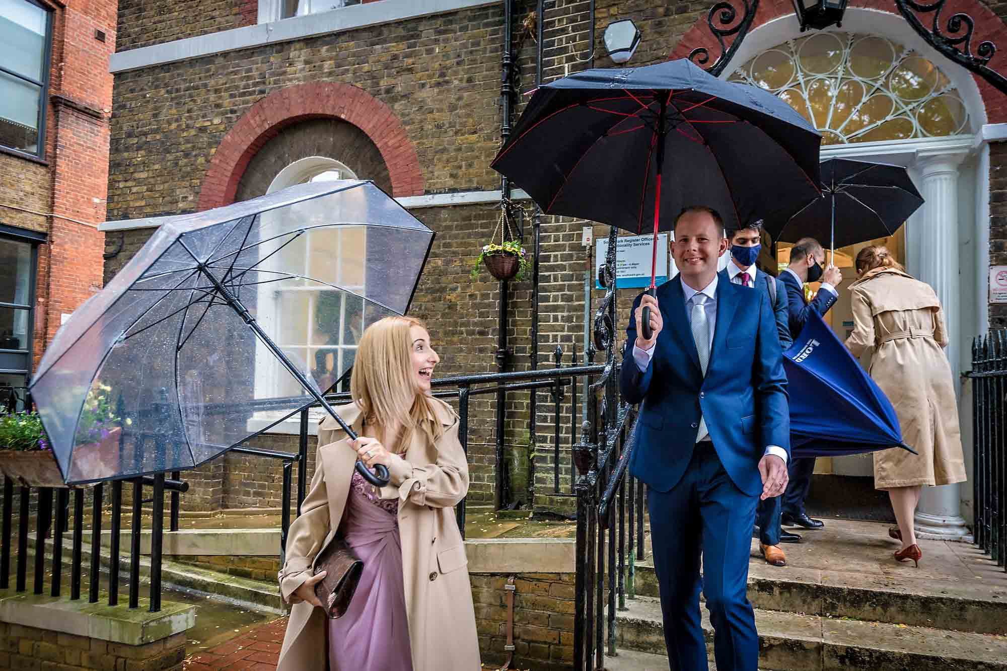 The newlyweds leave Southwark Register Office with umbrellas