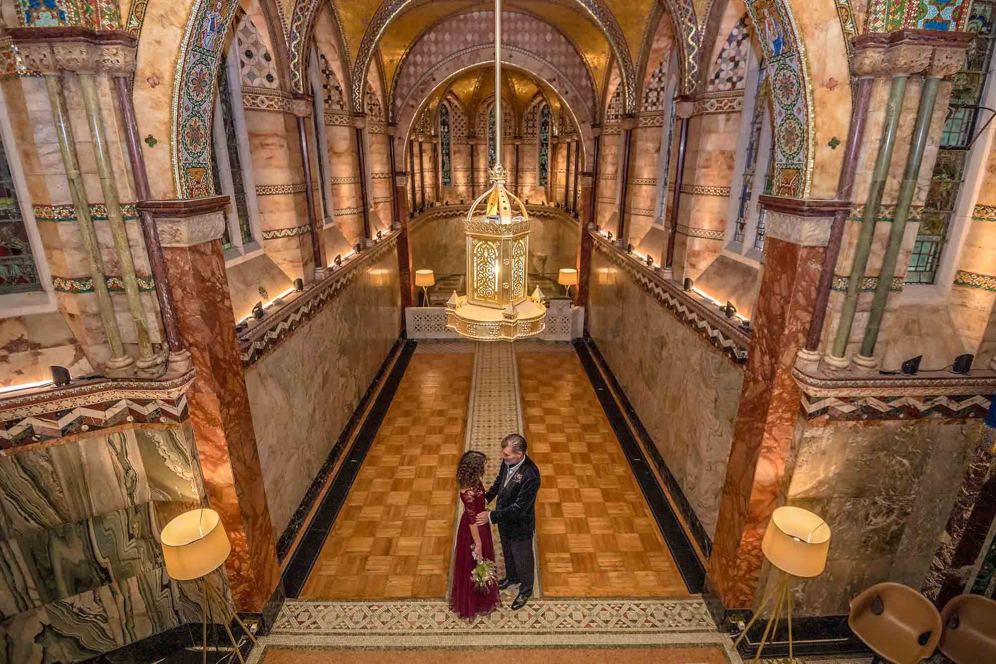 The groom holds his bride at their short wedding in Fitzrovia Chapel in Central London - taken from the balcony.