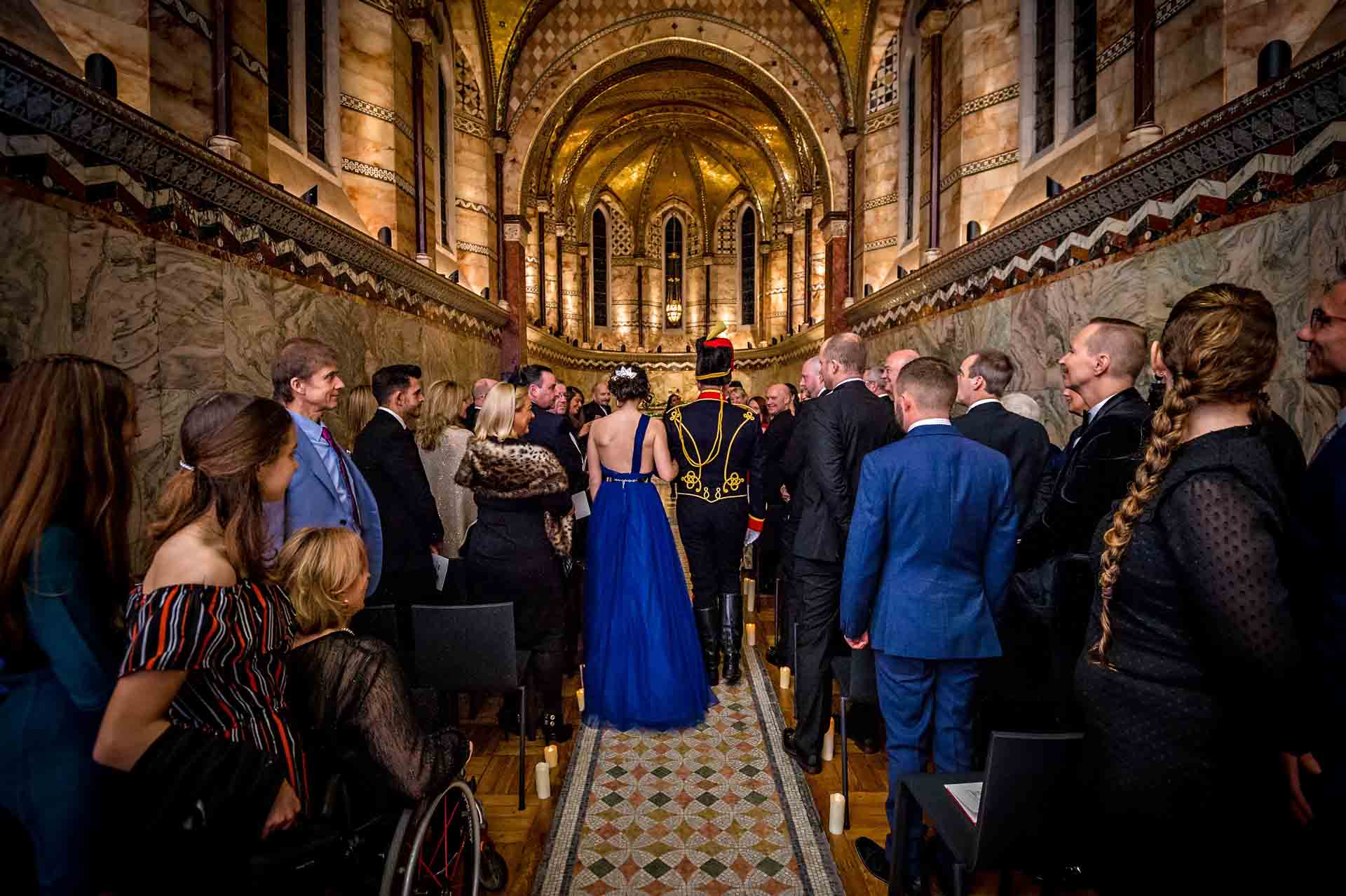 The groom and his daughter walking down the Fitzrovia Chapel aisle as guests watch