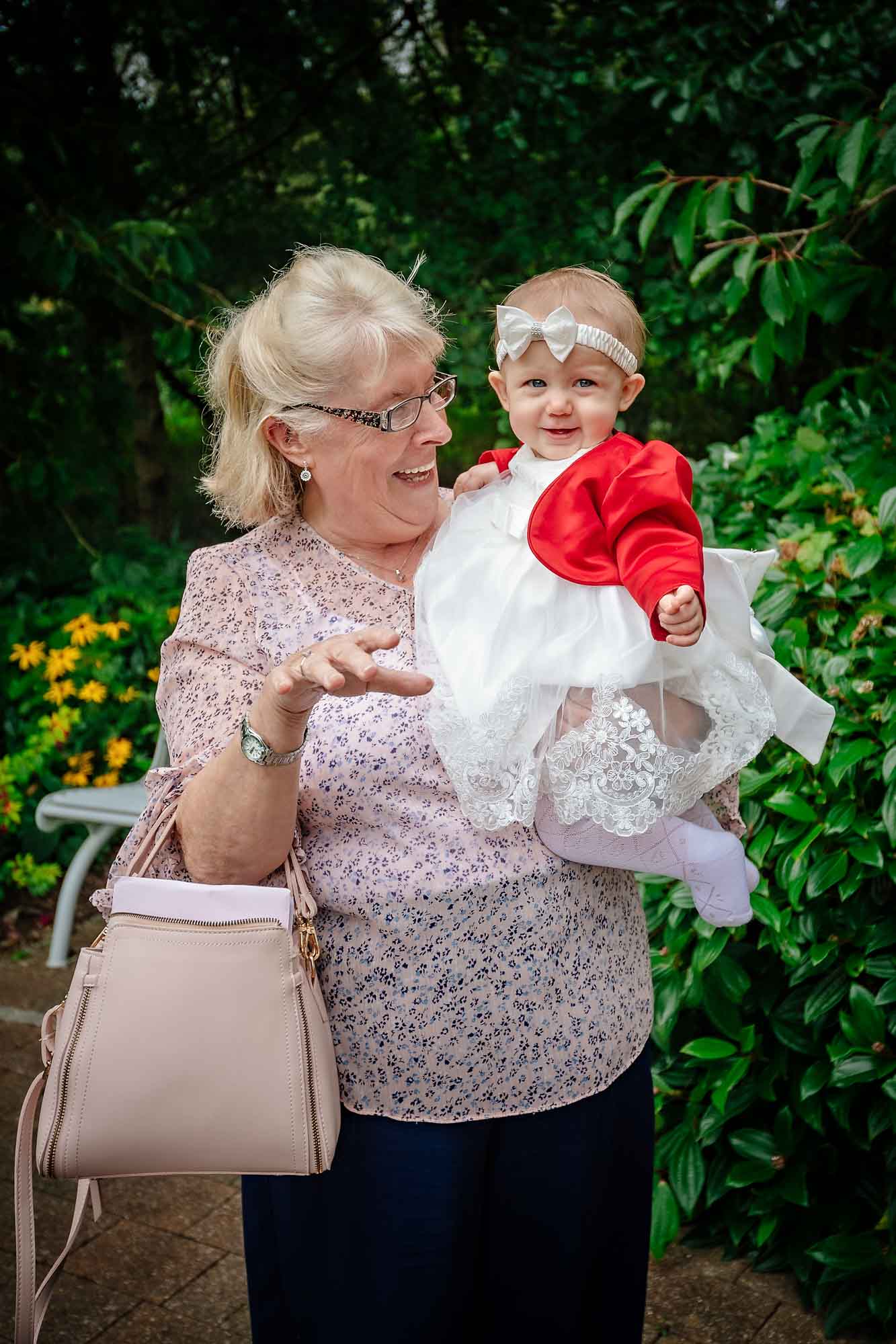 A happy baby girl's grandma holds her in gardens at a Penallta House wedding