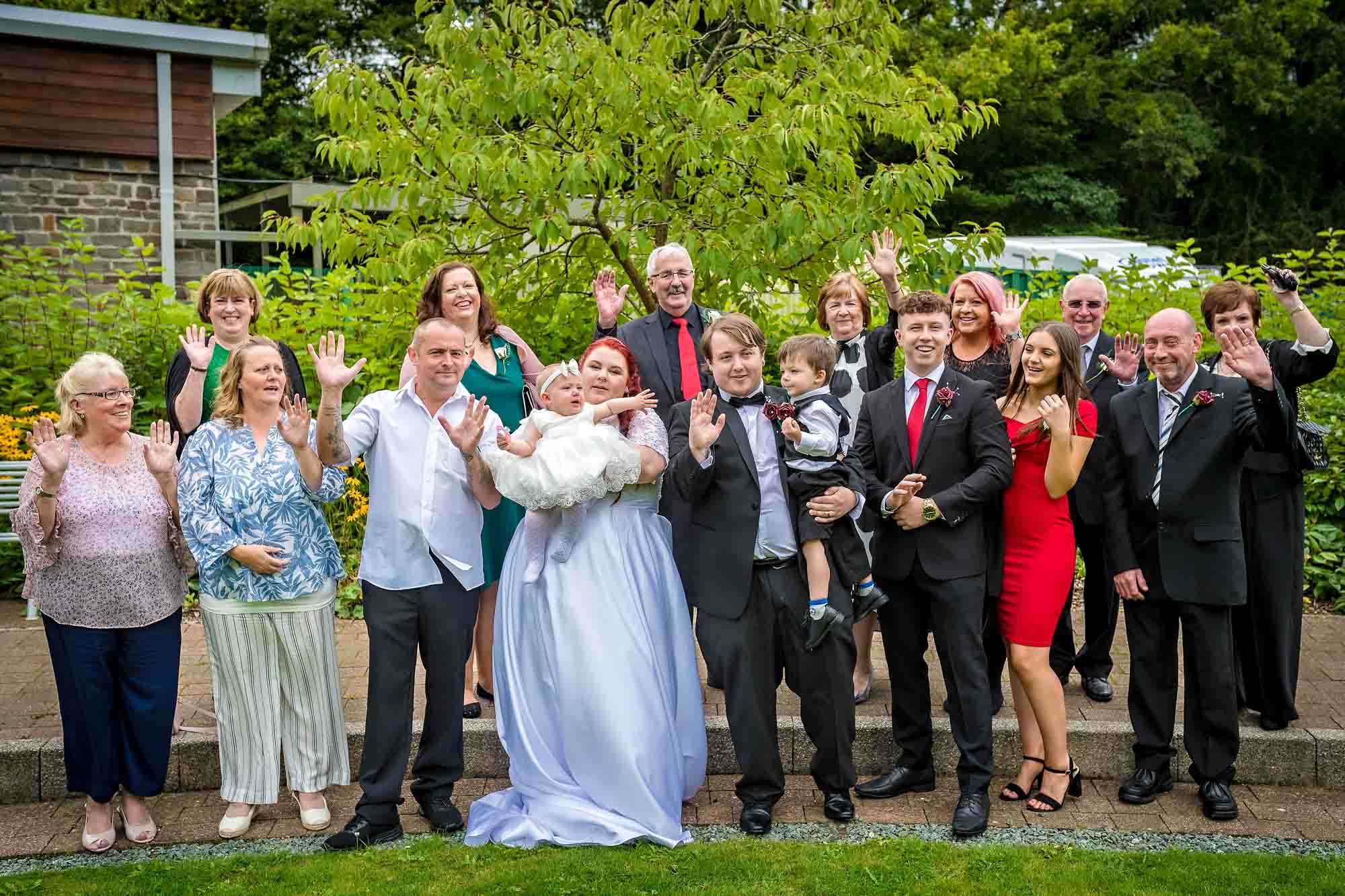 Whole wedding party waving at camera in garden of Penallta House, Caerphilly