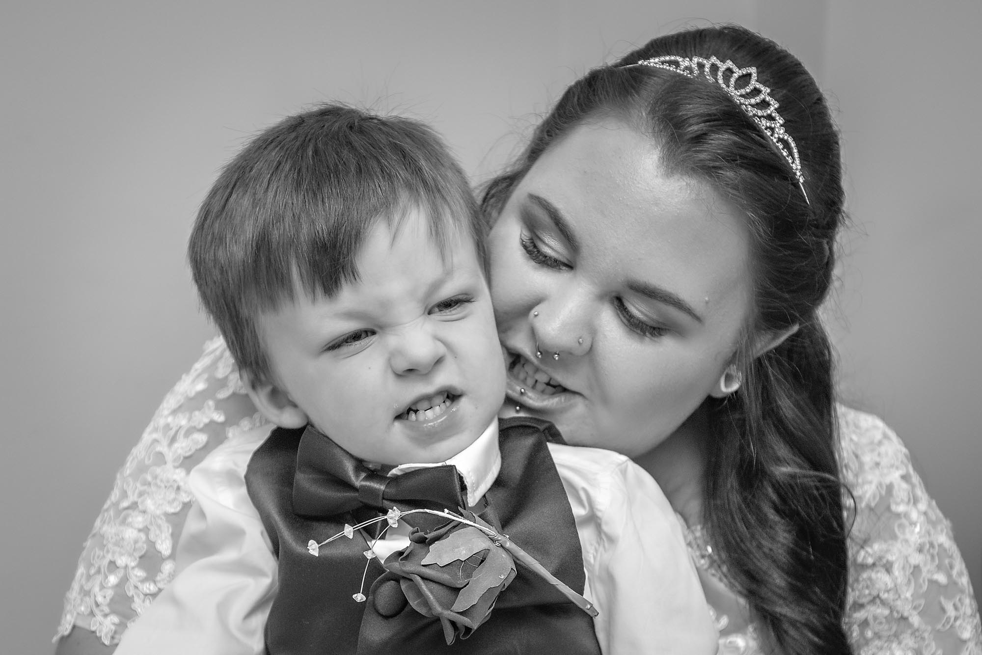 Bride with son pulling grimace at wedding
