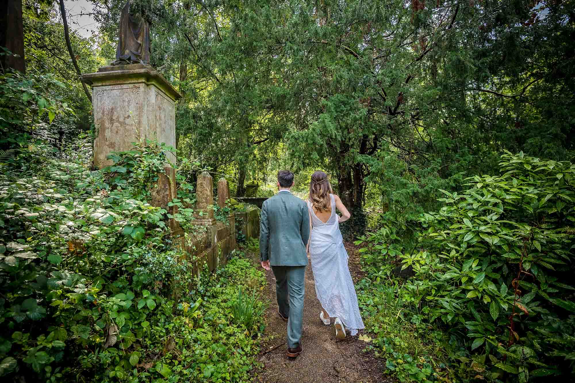 Couple walking away from camera past some gravestones at Arnos Vale Cemetery