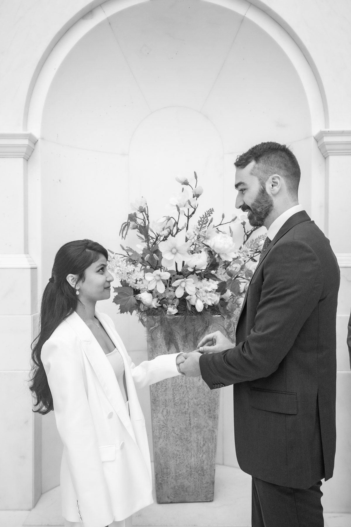 Groom placing ring on finger of bride on the Marble Staircase at Camden Town Hall