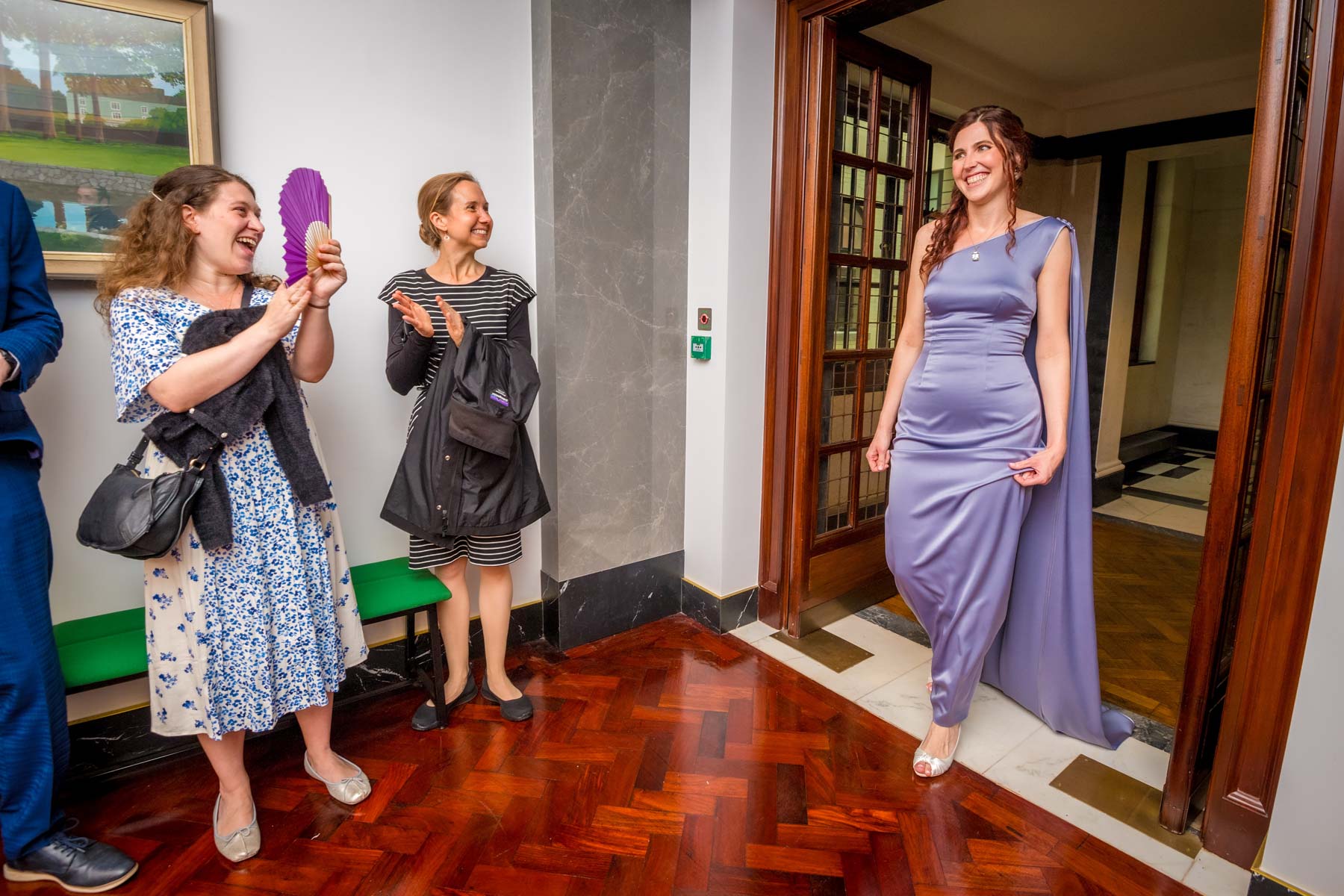 Bride in purple dress entering the reception area where wedding guests are clapping at Camden Town Hall