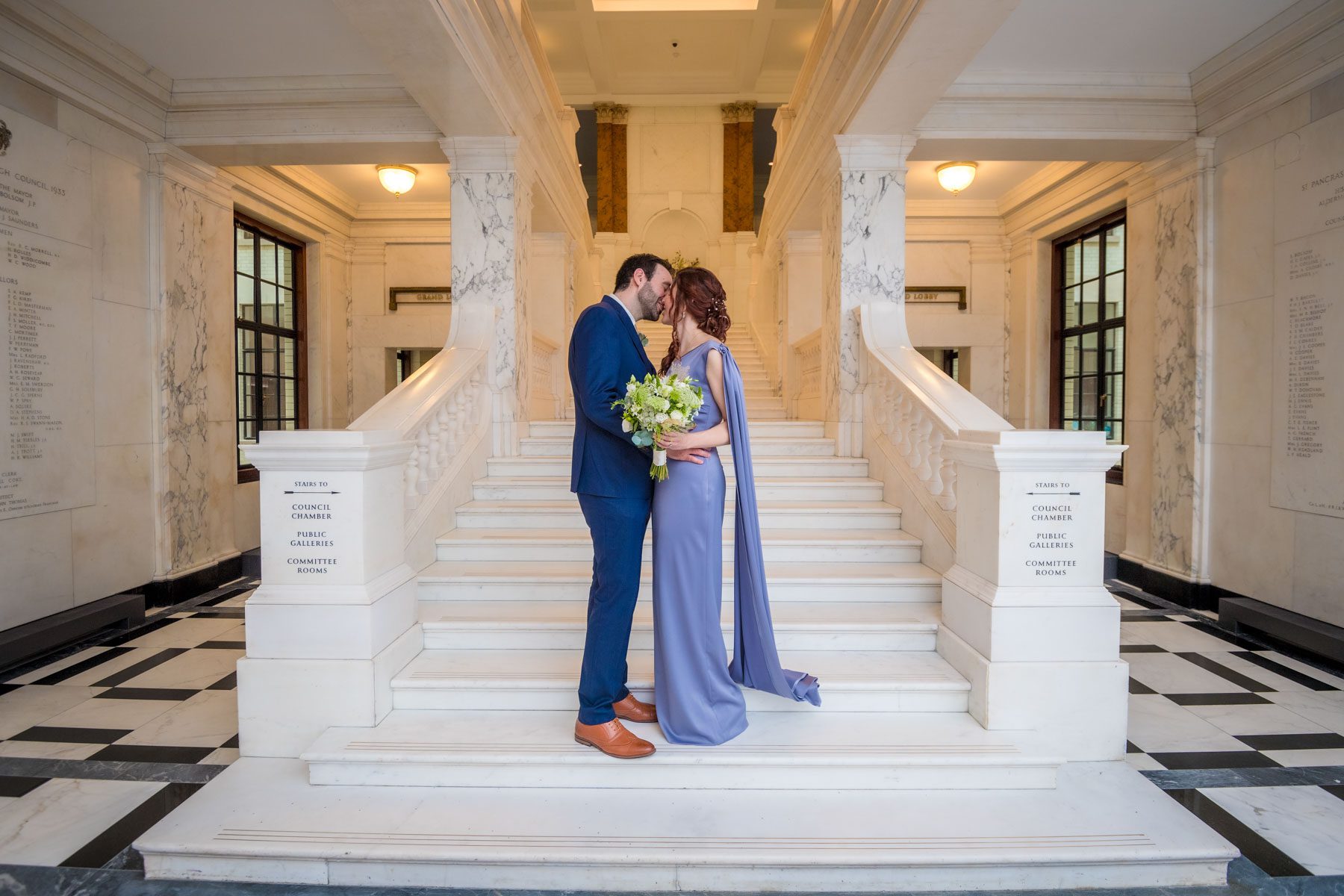 Newlyweds kissing at the foot of the Marble Staircase at Camden Town Hall