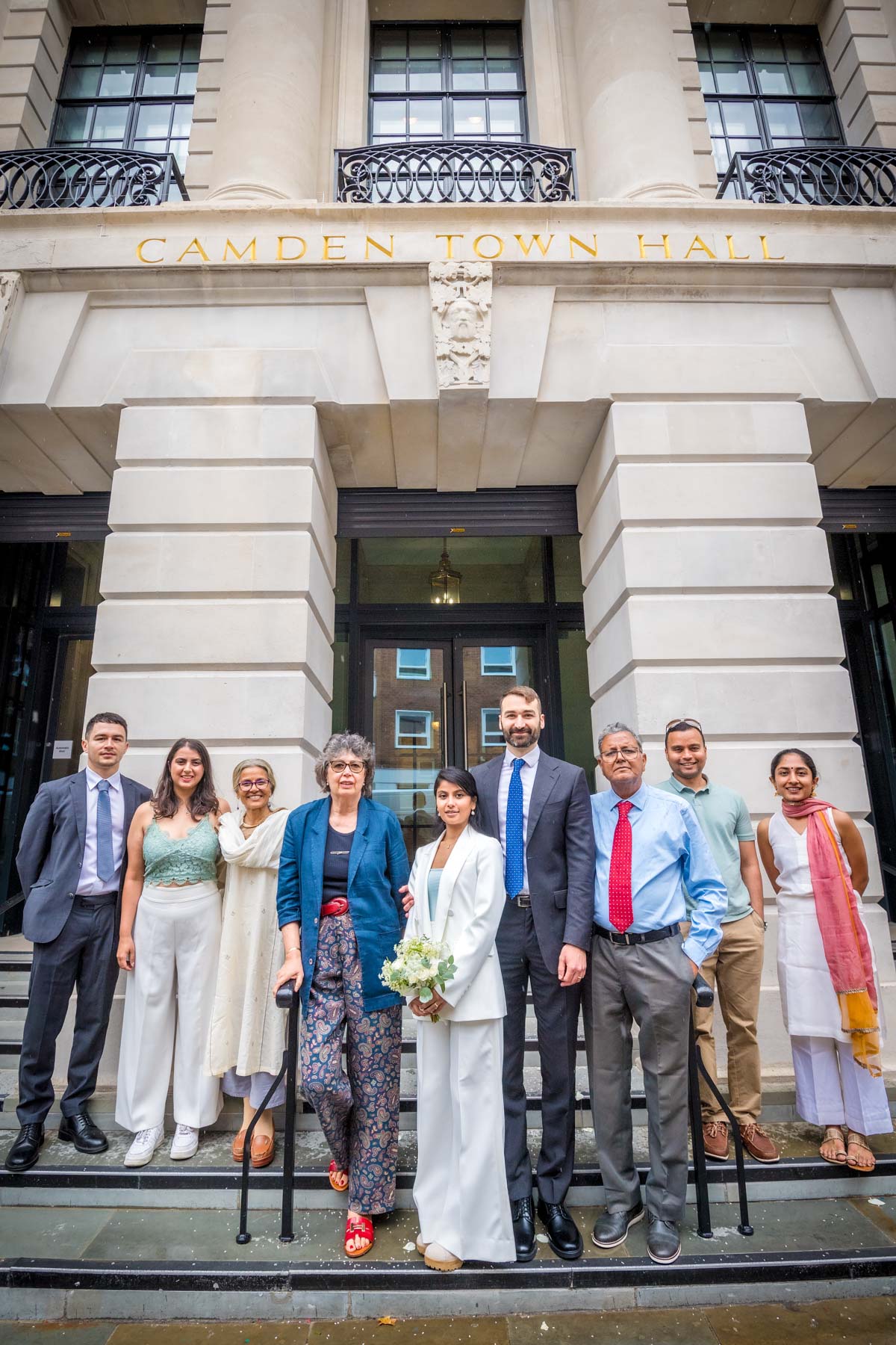 Newlyweds posing with friends and family outside Camden Town Hall