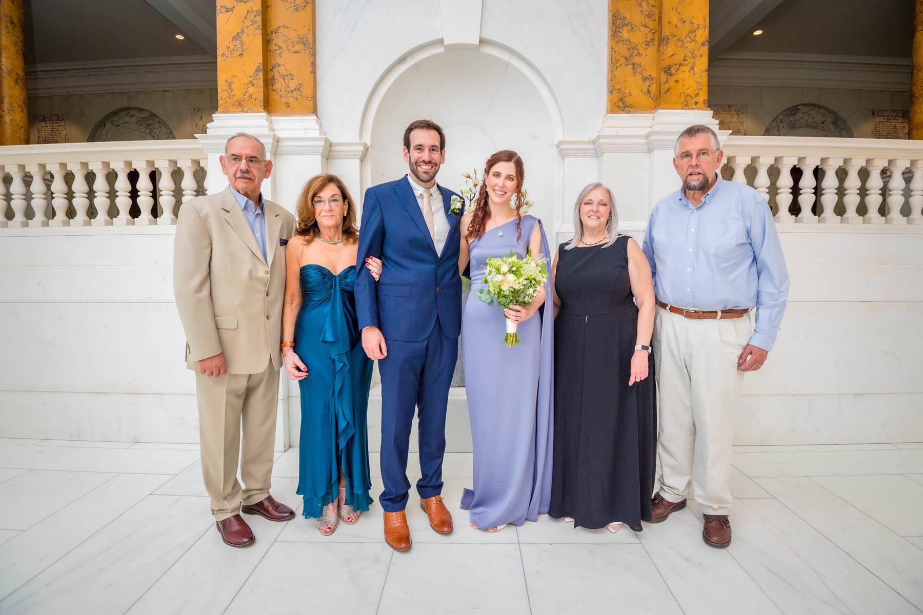 Bride and groom with both sets of parents posing at the top of the Marble Staircase at Camden Town Hall