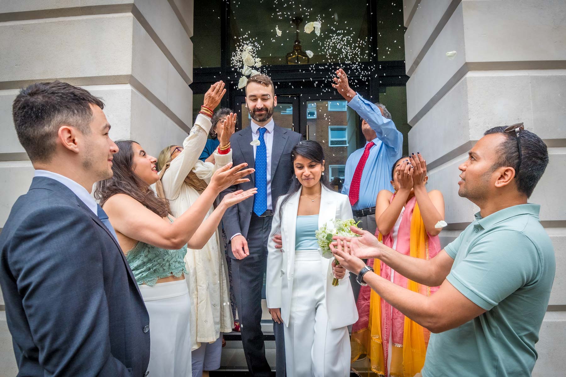 Seven guests throw confetti over the bride and groom outside Camden Town Hall