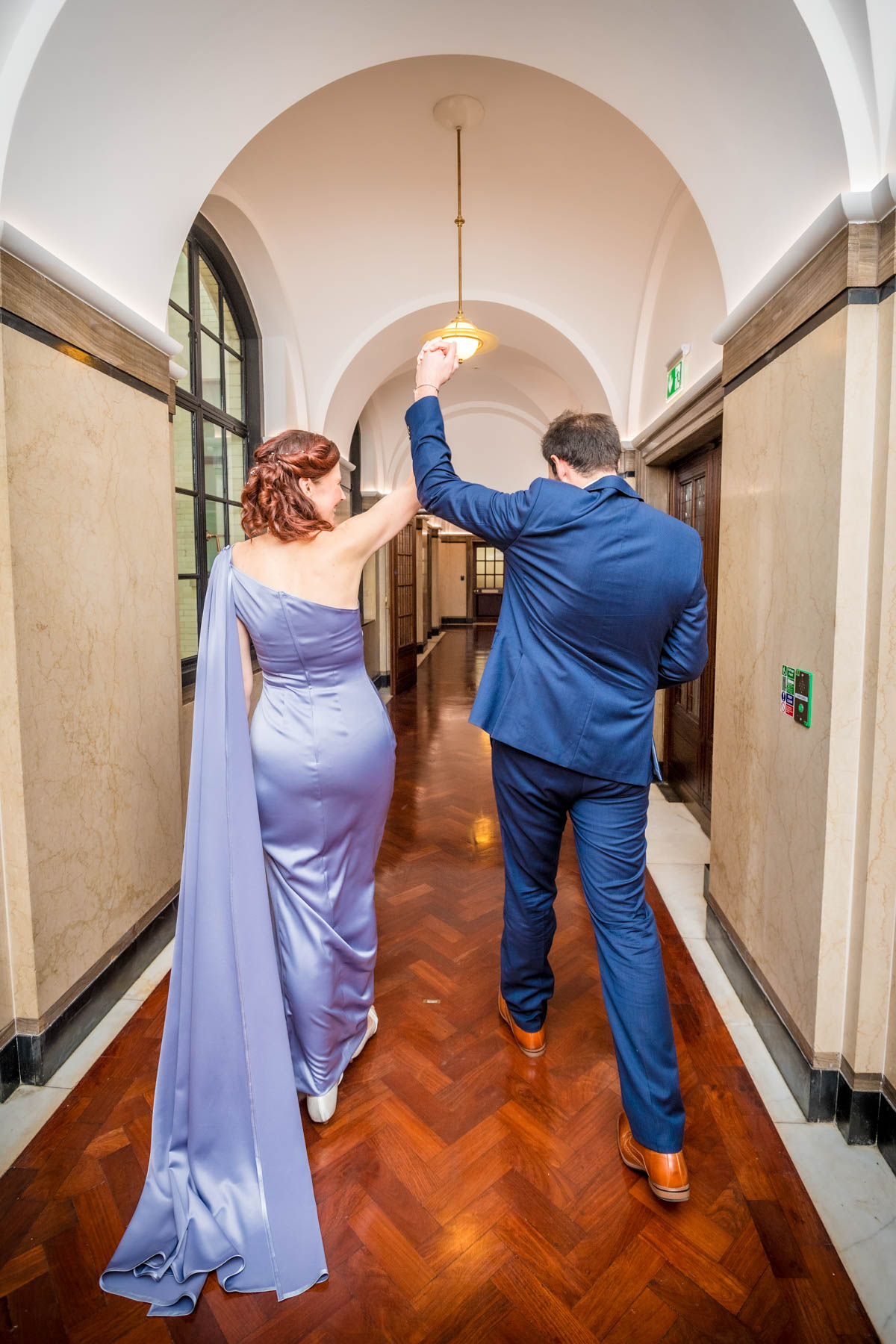 Newlyweds walking away from camera and pumping arms in the air after their wedding ceremony