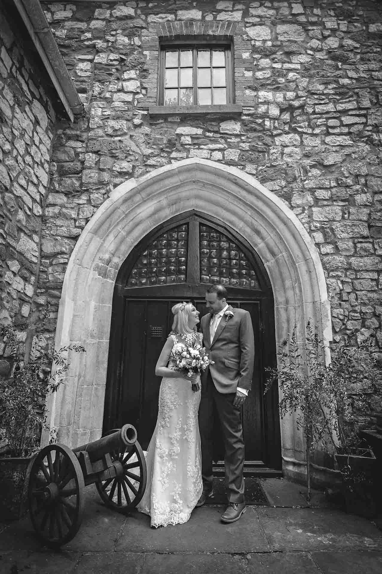 Newly-weds pose outside arched doorway at Pencoed House