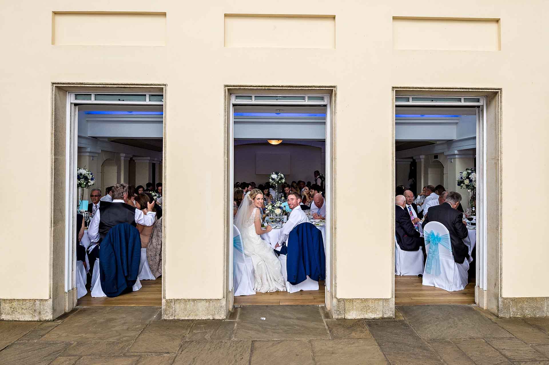 Bride and Groom at Wedding Breakfast Looking Out of Belvedere Room Door at Pembroke Lodge