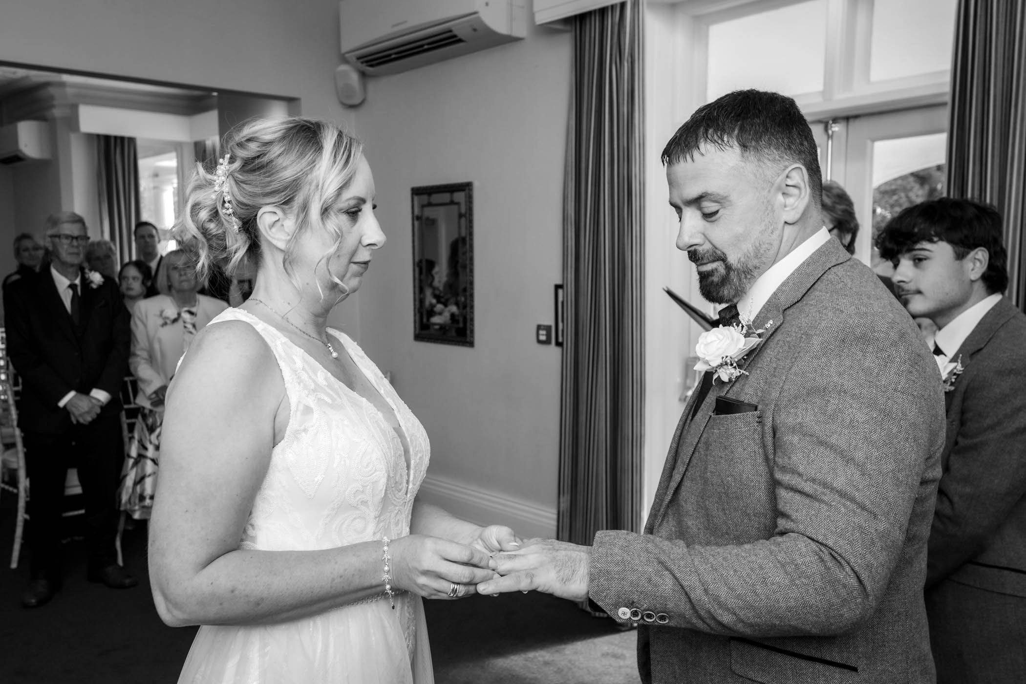 The bride places the ring on her groom's finger - black and white photograph