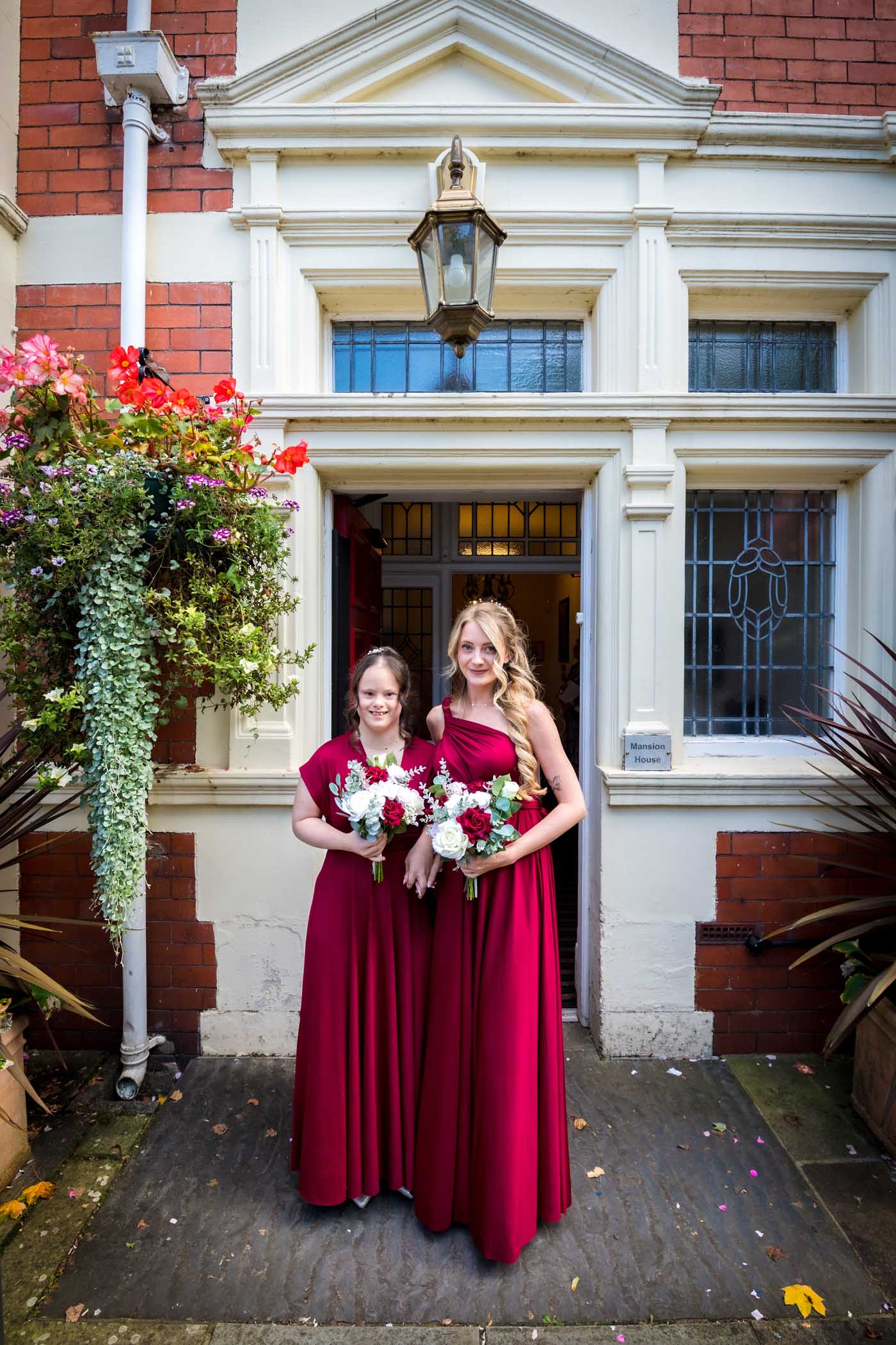 The bridesmaids in burgundy dresses pose outside the front door to the Mansion House in Newport