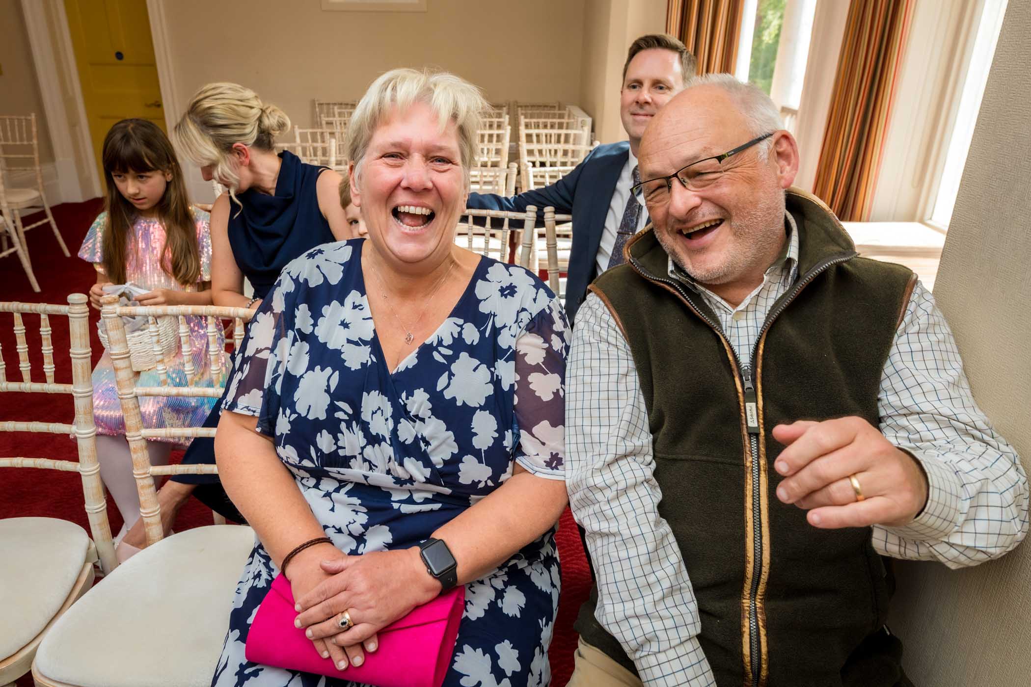Two elderly wedding guests laughing when they realise they're being photographed