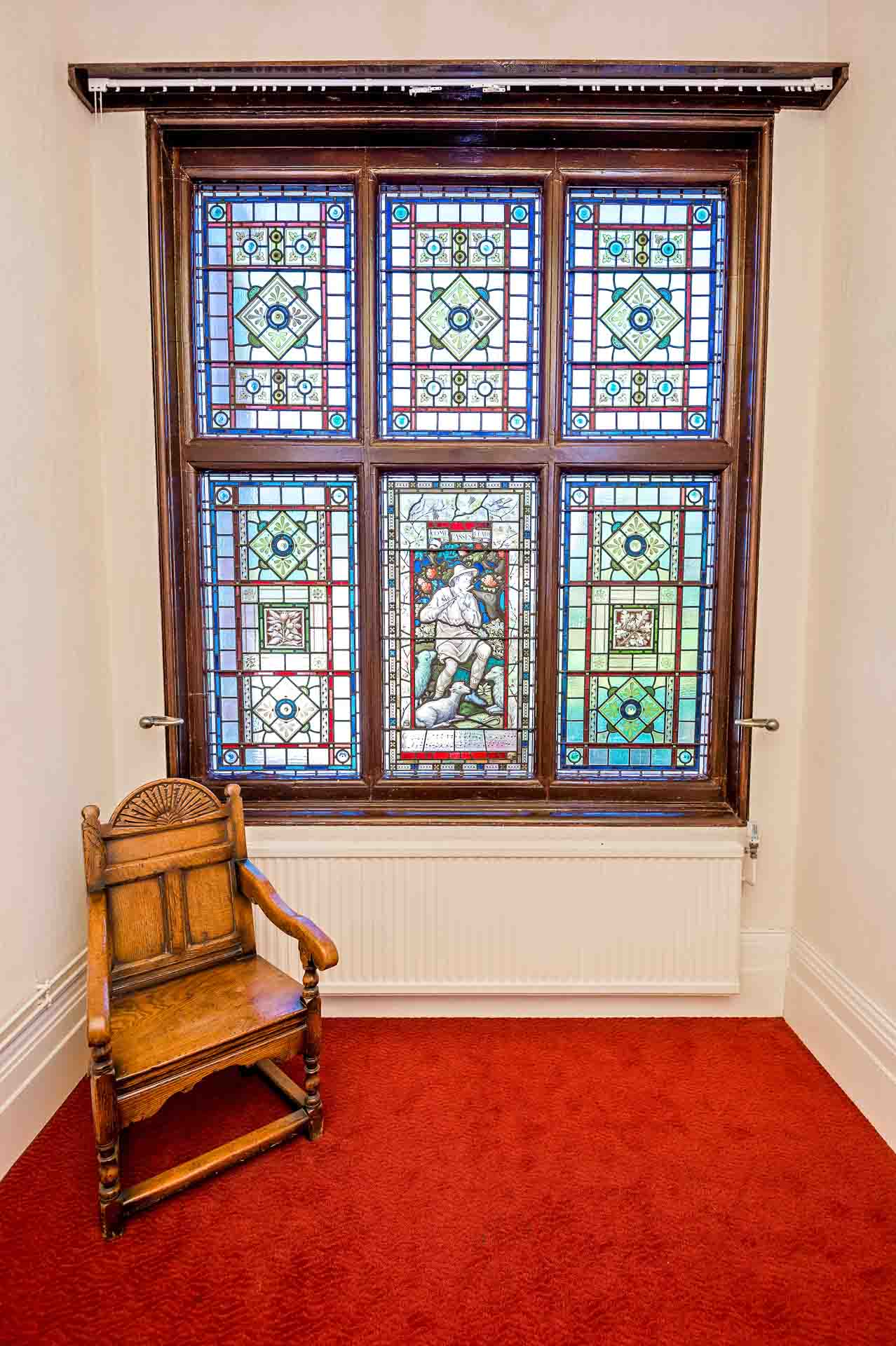 Old wooden chair in front of stained glass window on landing of the Mansion House in Newport