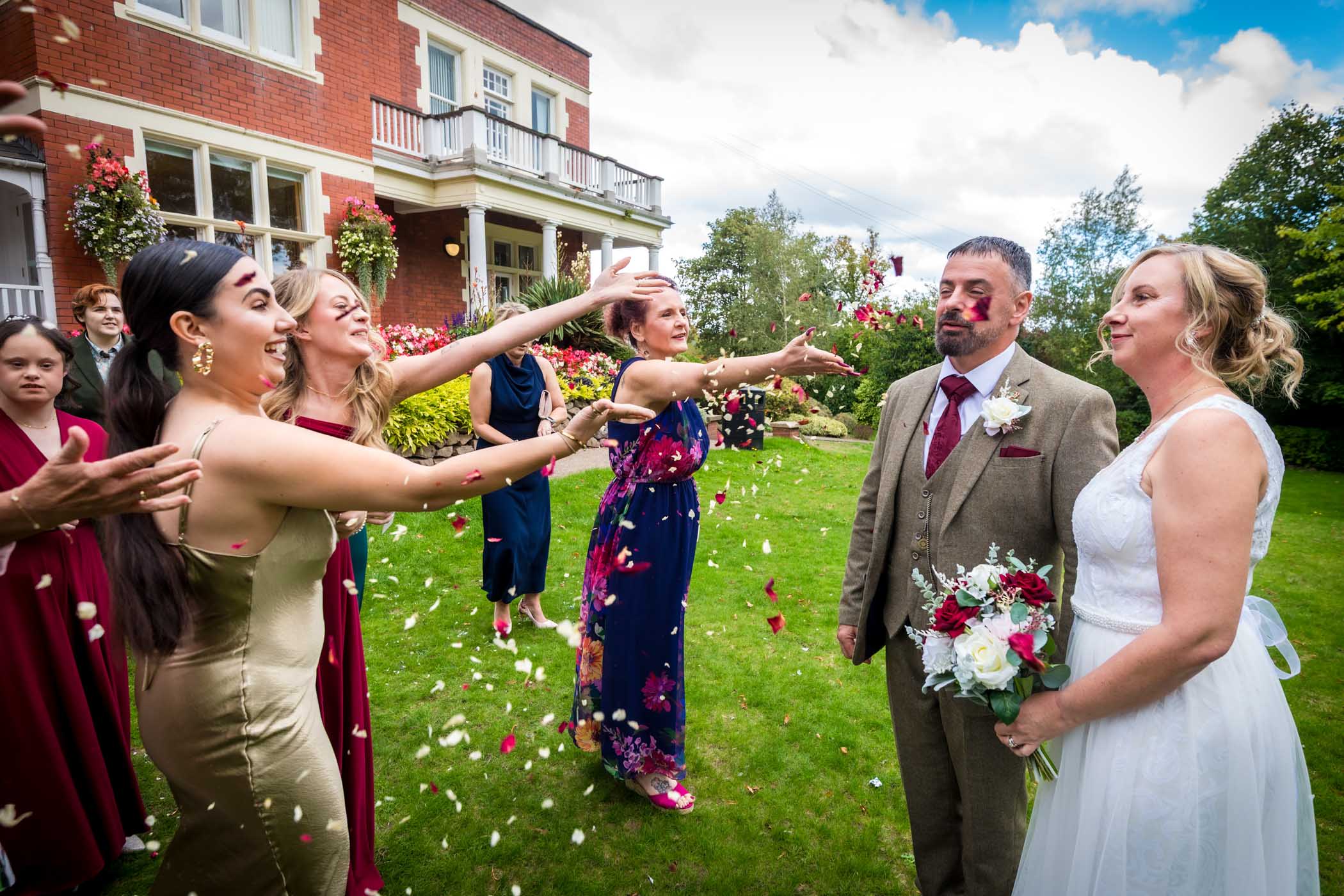 Couple standing still whilst guests throw the confetti over them