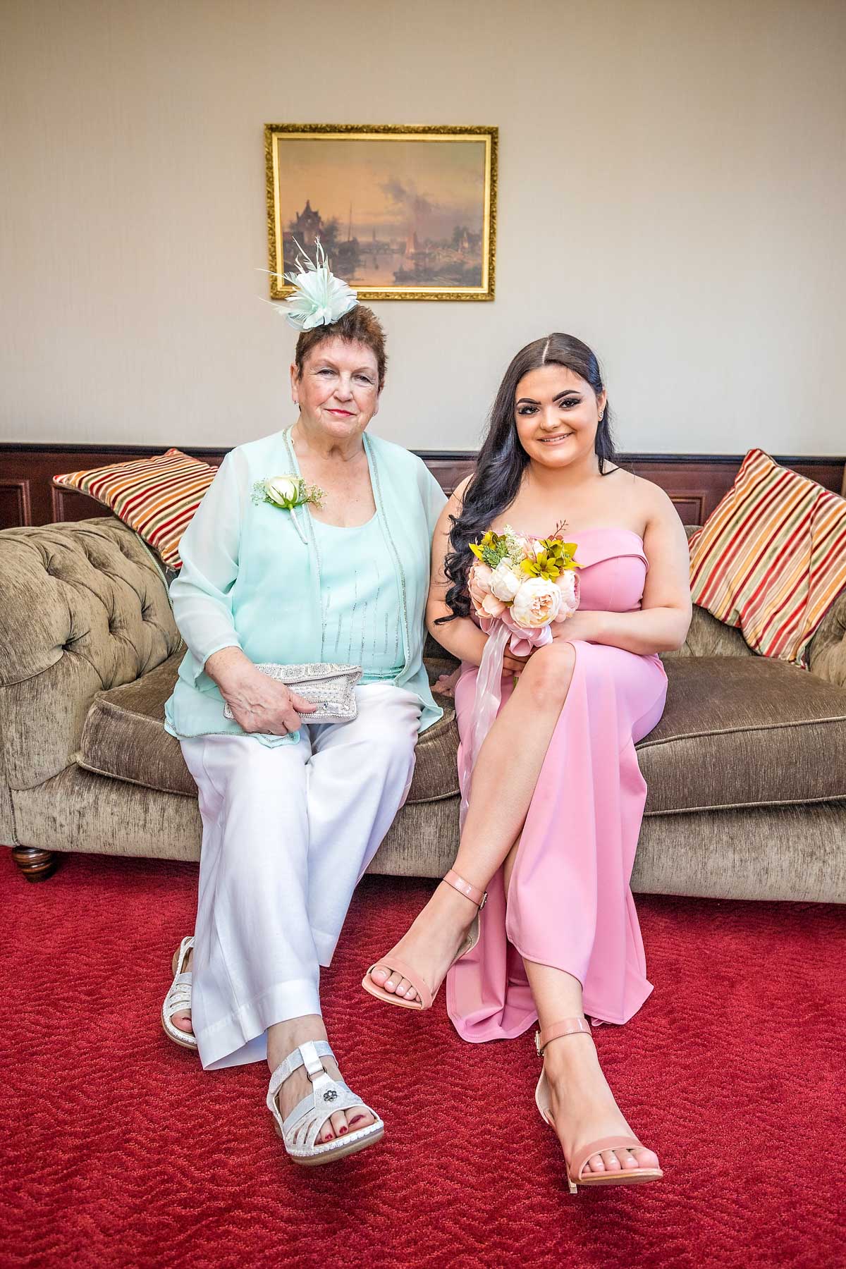 Mature and young ladies sitting next to each other on couch at wedding