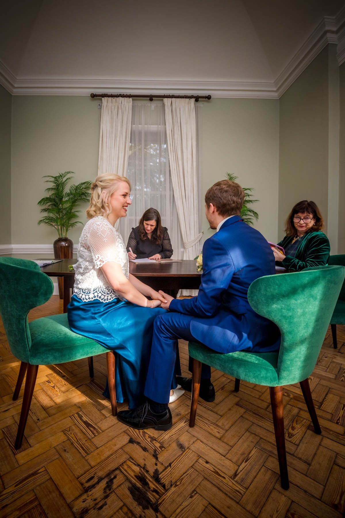 Seated newlyweds holding hands after wedding ceremony.