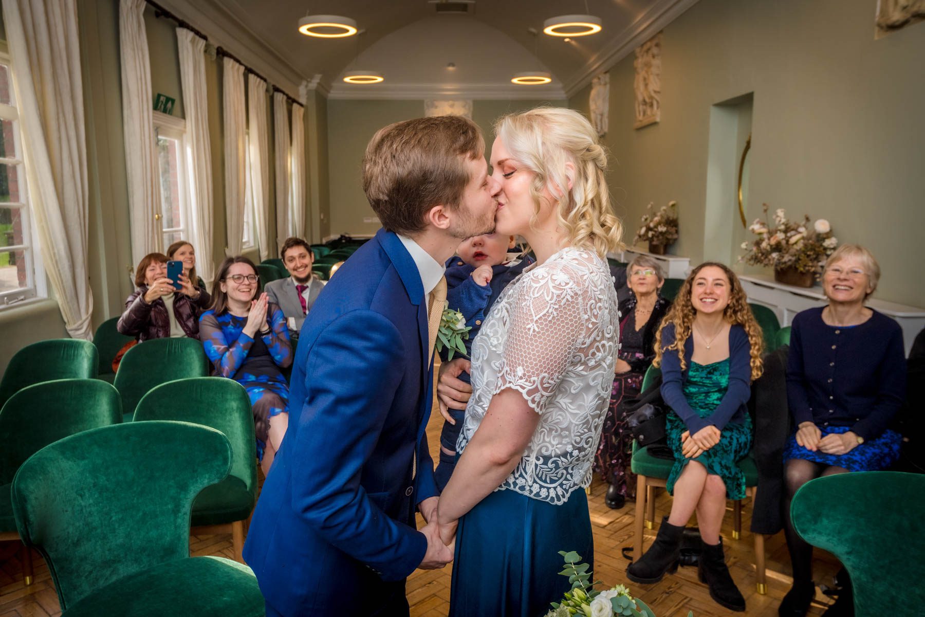 Couple having first kiss with guests in the background at York House.