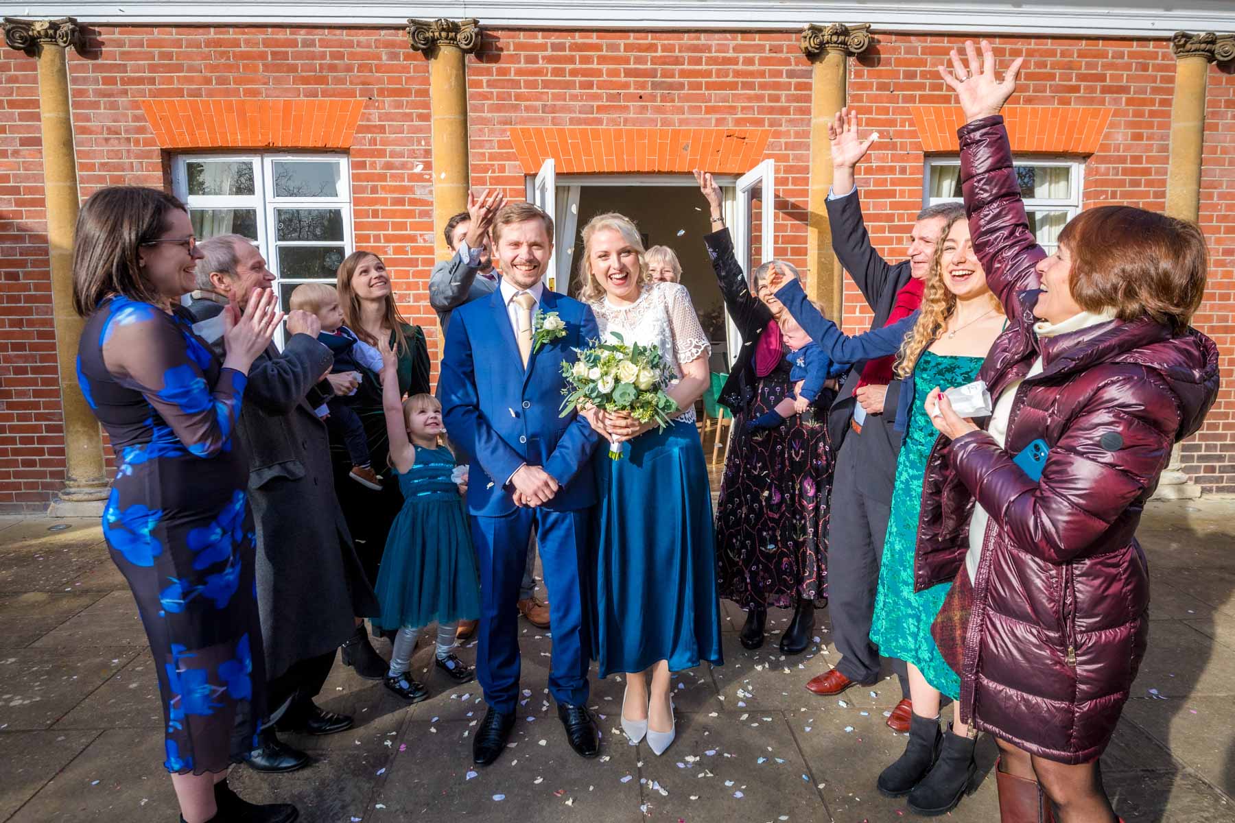 Guests throw confetti over newlyweds as they leave the Loggia Room in York House, Twickenham.