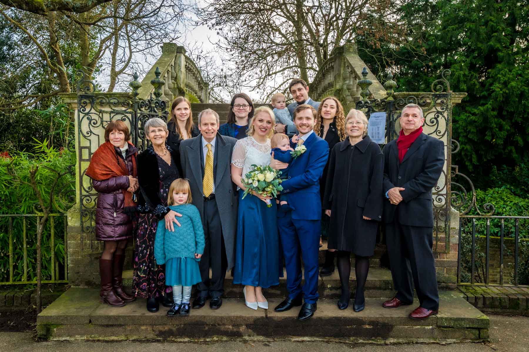 Small wedding party pose for photos on steps to bridge at York House in Twickenham.