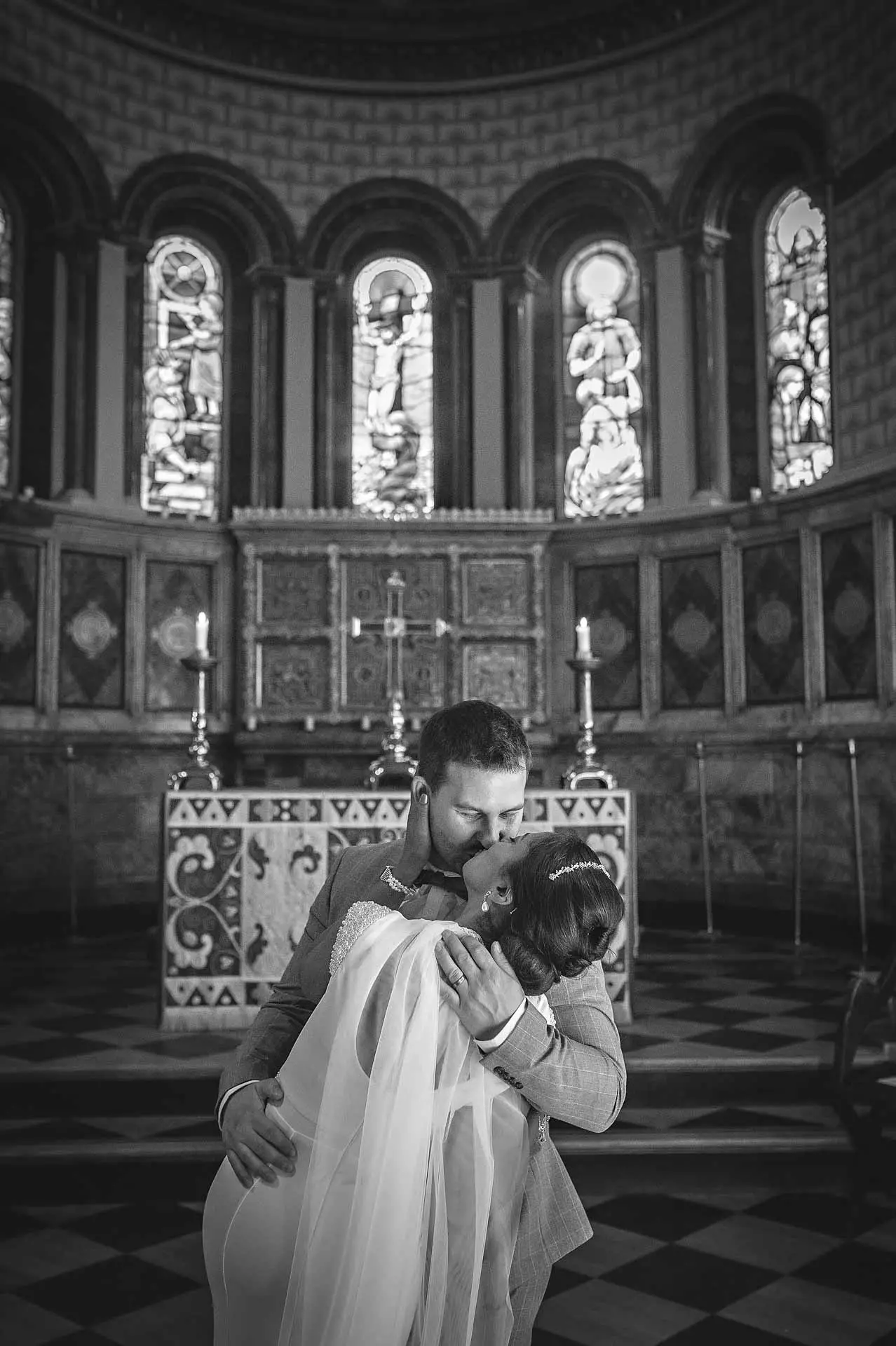 bruidegom die de bruid hartstochtelijk kuste in zijn armen in King 's College Chapel in Londen