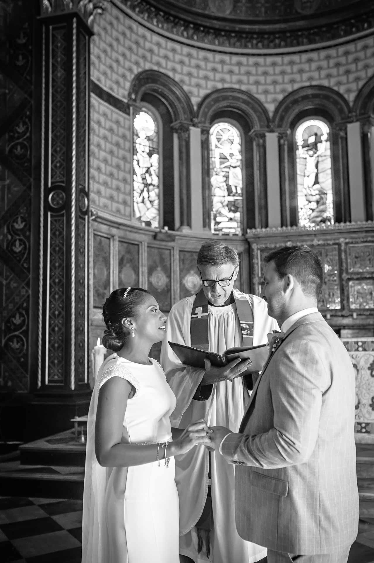 Bride placing ring on Groom's finger at King's College Chapel Wedding