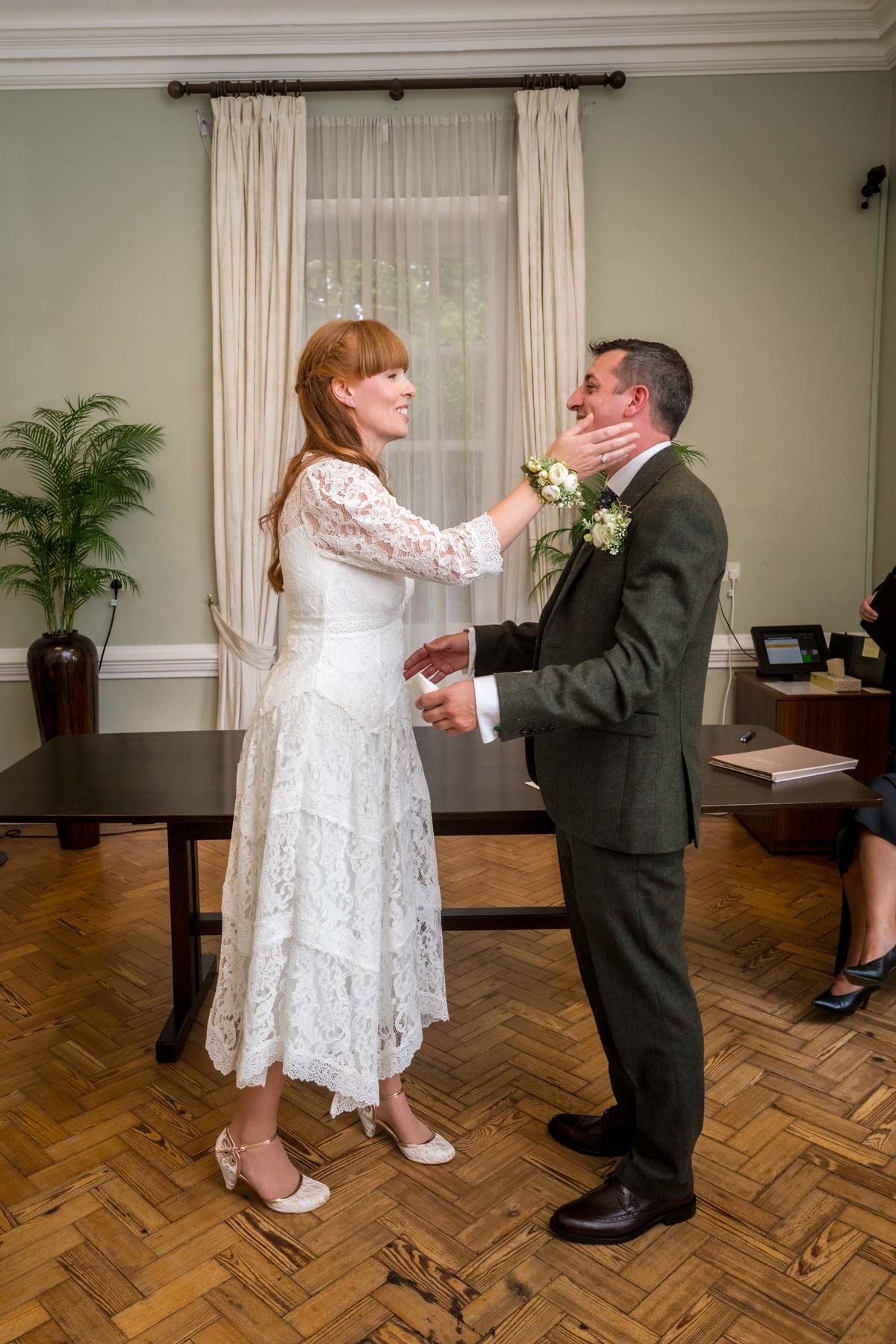 Couple facing each other during wedding with bride touching groom's face