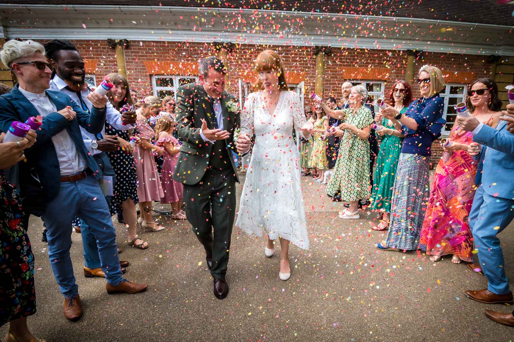 Bride and groom brave a confetti shower by their guests outside York House in Twickenham