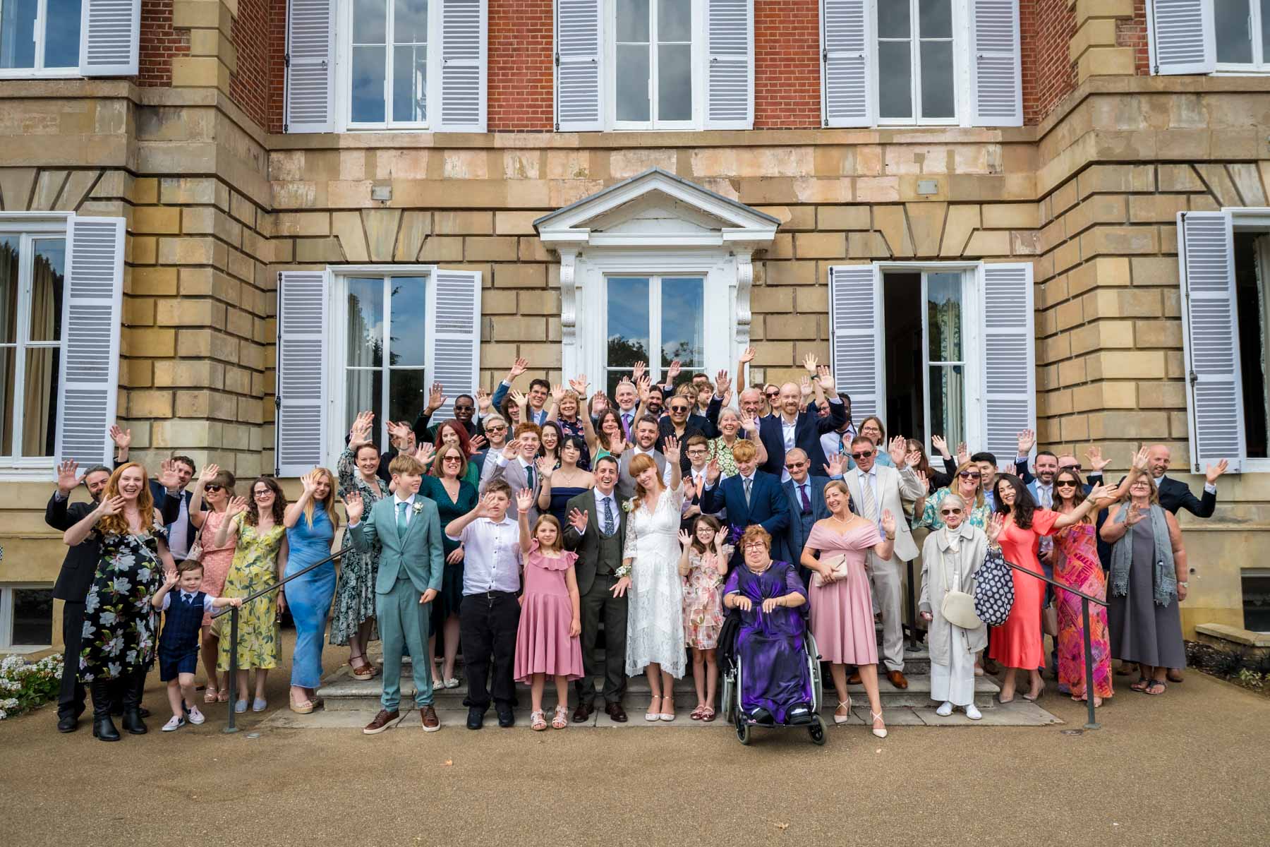 Whole wedding party posed at the back of York House waving at camera